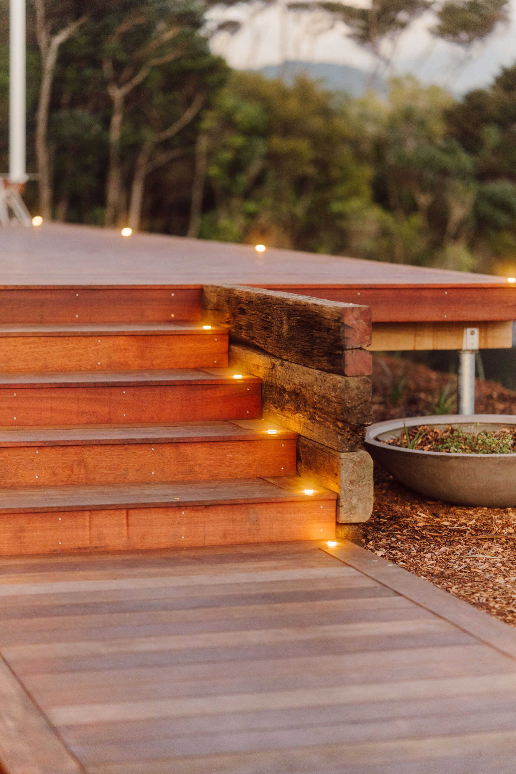 Explore the outdoor living spaces of a modern Coromandel cabin, featuring expansive timber decking, a sunken outdoor bathtub, covered dining pavilion, glamping tents and spectacular coastal views. Inspiration for small holiday homes and outdoor entertaining.