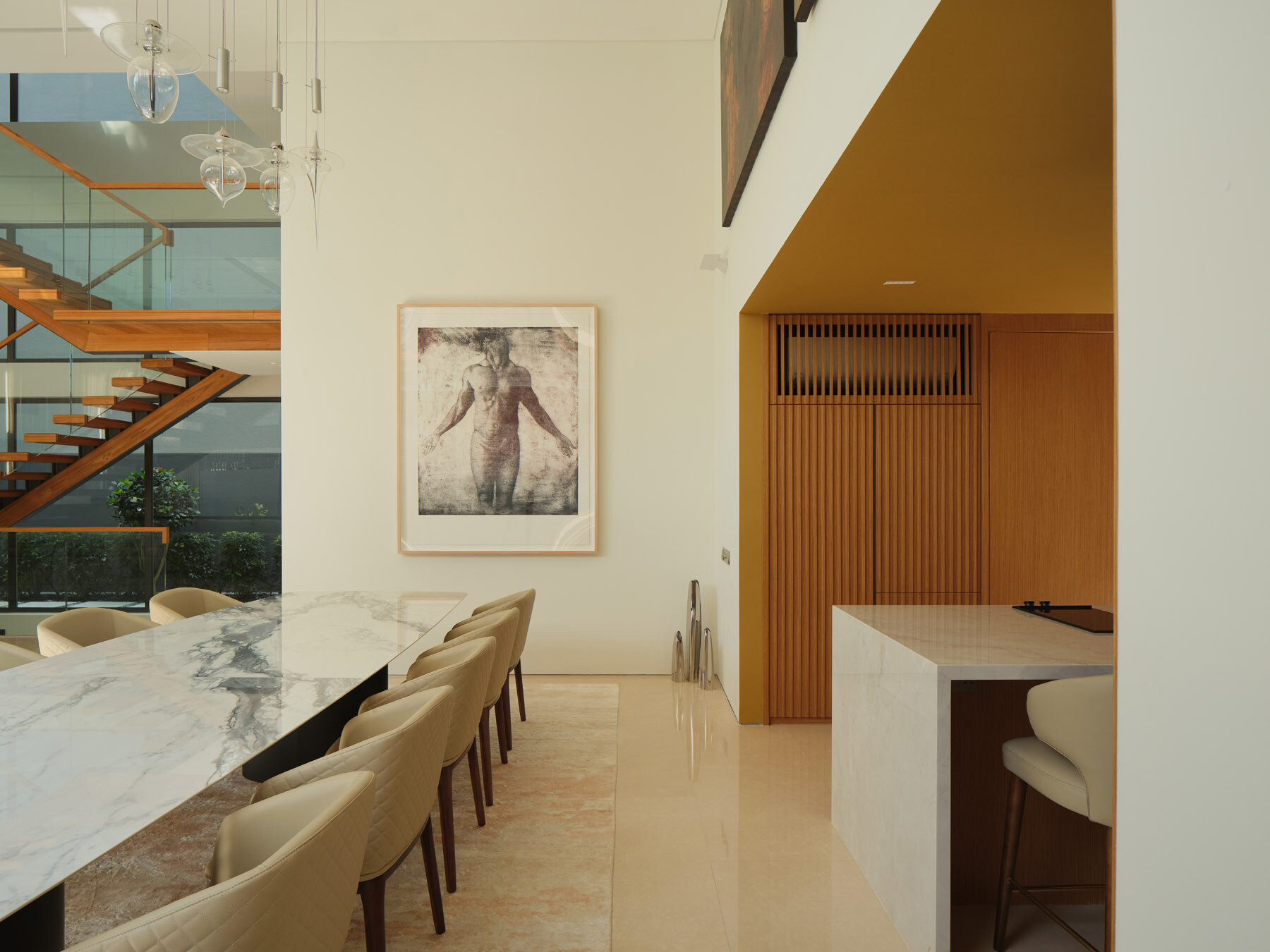 Discover a contemporary dining room and kitchen in Singapore, featuring a long marble dining table, upholstered seating, timber cabinetry, and a minimalist stone kitchen island.