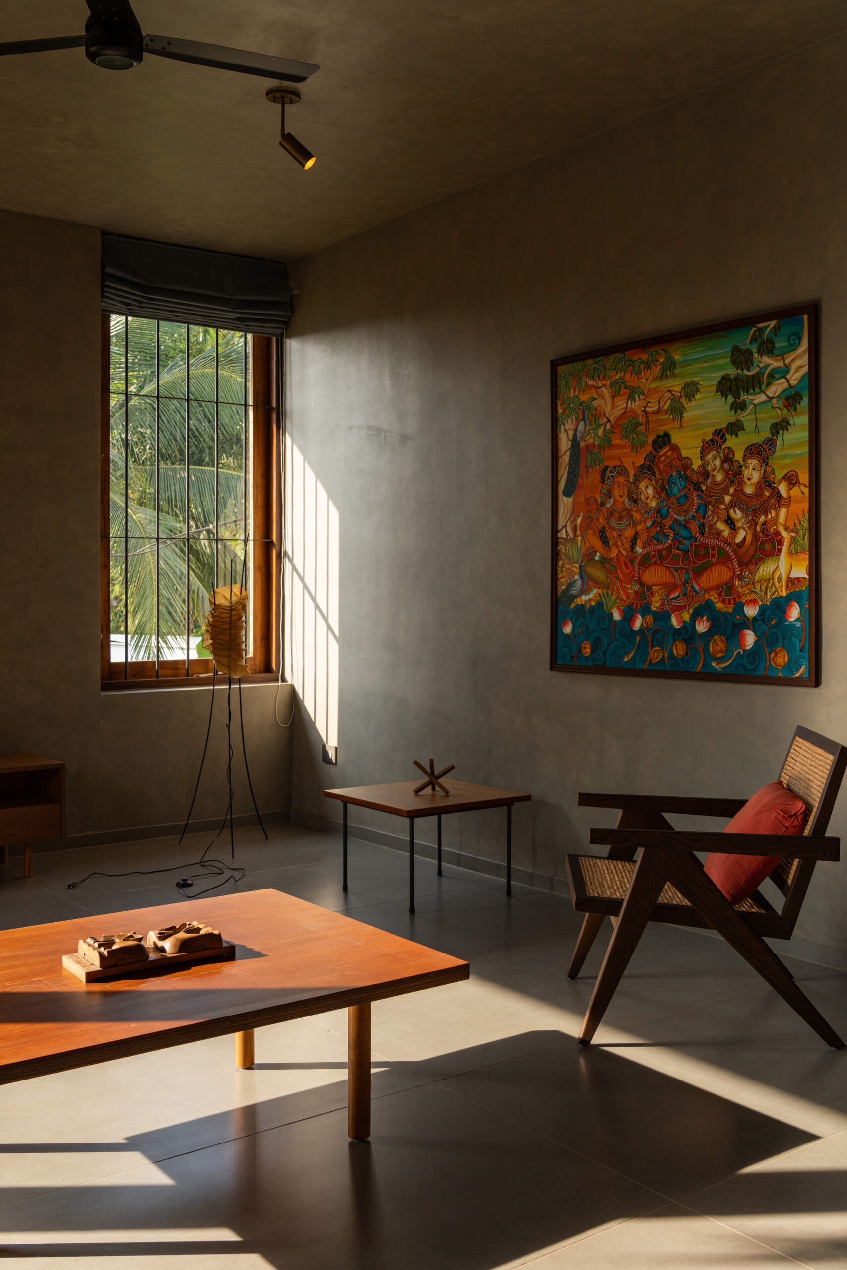 An upper-floor entertainment room with wooden shutters, a green daybed, a built-in desk, and treetop views shows how contemporary design can embrace its natural surroundings.