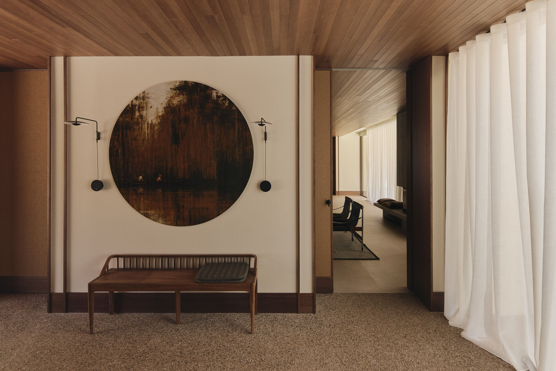 Step inside Casa Tossal and explore its modern entryway, featuring floating-style concrete garden steps, wood ceilings, large wooden doors, sculptural artwork, and a minimalist wooden bench.