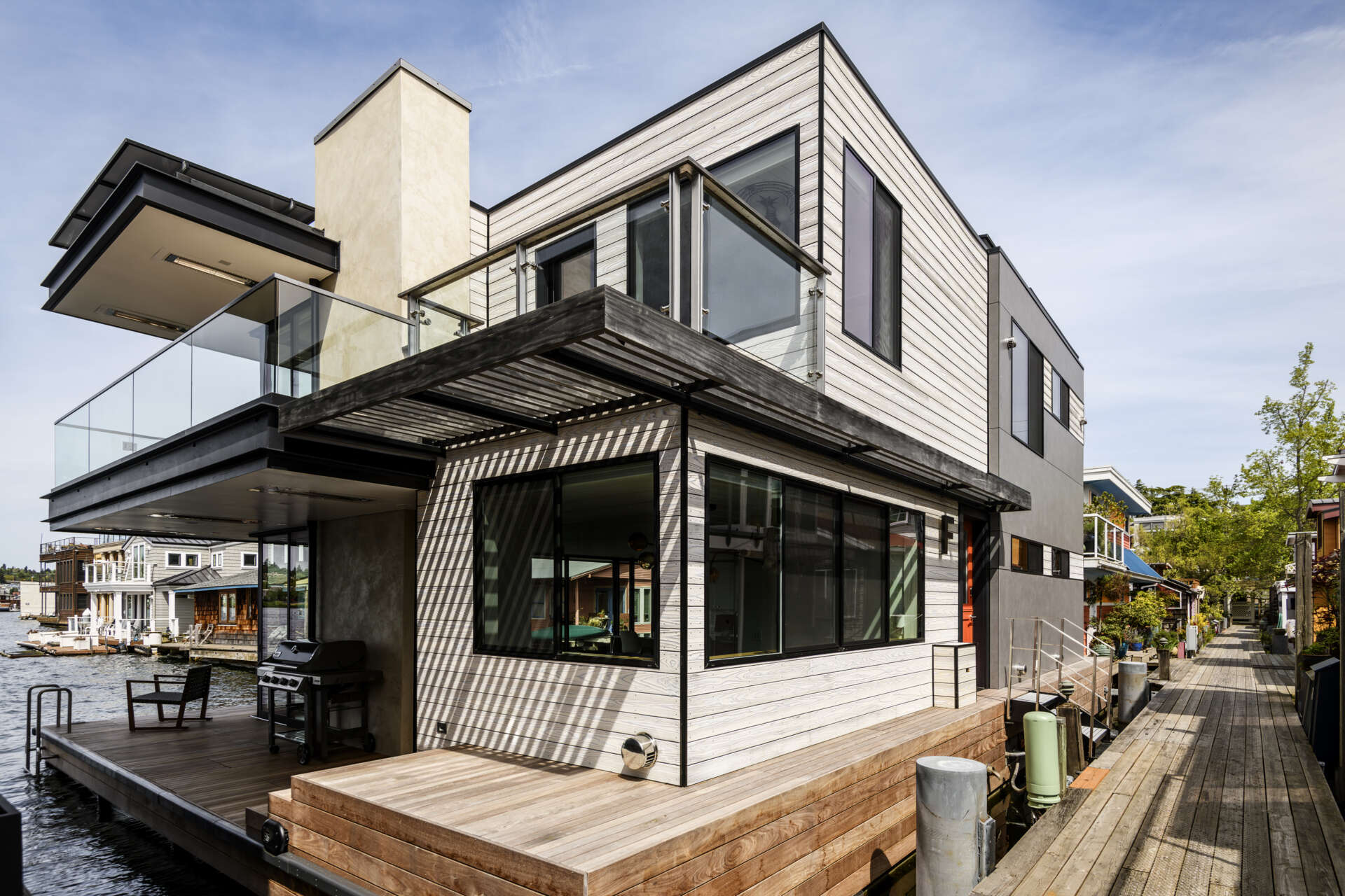 Explore the architecture of Modern Beach House, a two-story floating home on Seattle's Lake Union by Hoshide Wanzer Architects + Interiors. Featuring weathered yakisugi siding, expansive sliding glass doors, glass balconies, and waterfront decks, this contemporary house combines modern architecture with practical floating-home design.