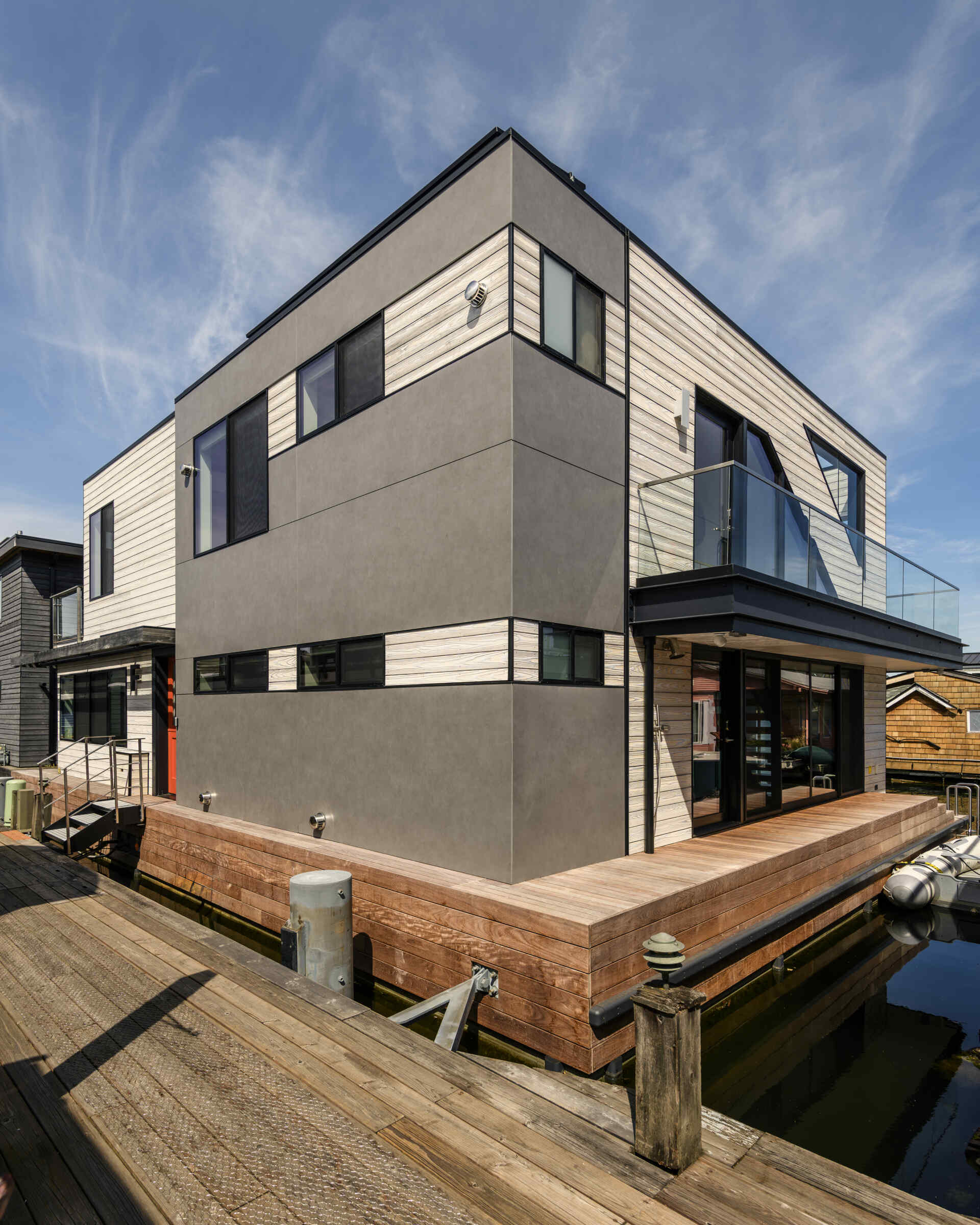 Explore the architecture of Modern Beach House, a two-story floating home on Seattle's Lake Union by Hoshide Wanzer Architects + Interiors. Featuring weathered yakisugi siding, expansive sliding glass doors, glass balconies, and waterfront decks, this contemporary house combines modern architecture with practical floating-home design.