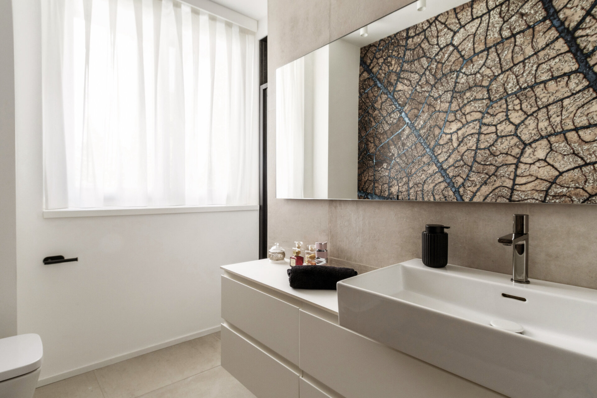 A hidden guest bathroom features dramatic tree-pattern wallpaper, a floating vanity, a large mirror, and a dark tiled shower, accessed from a textured hallway.