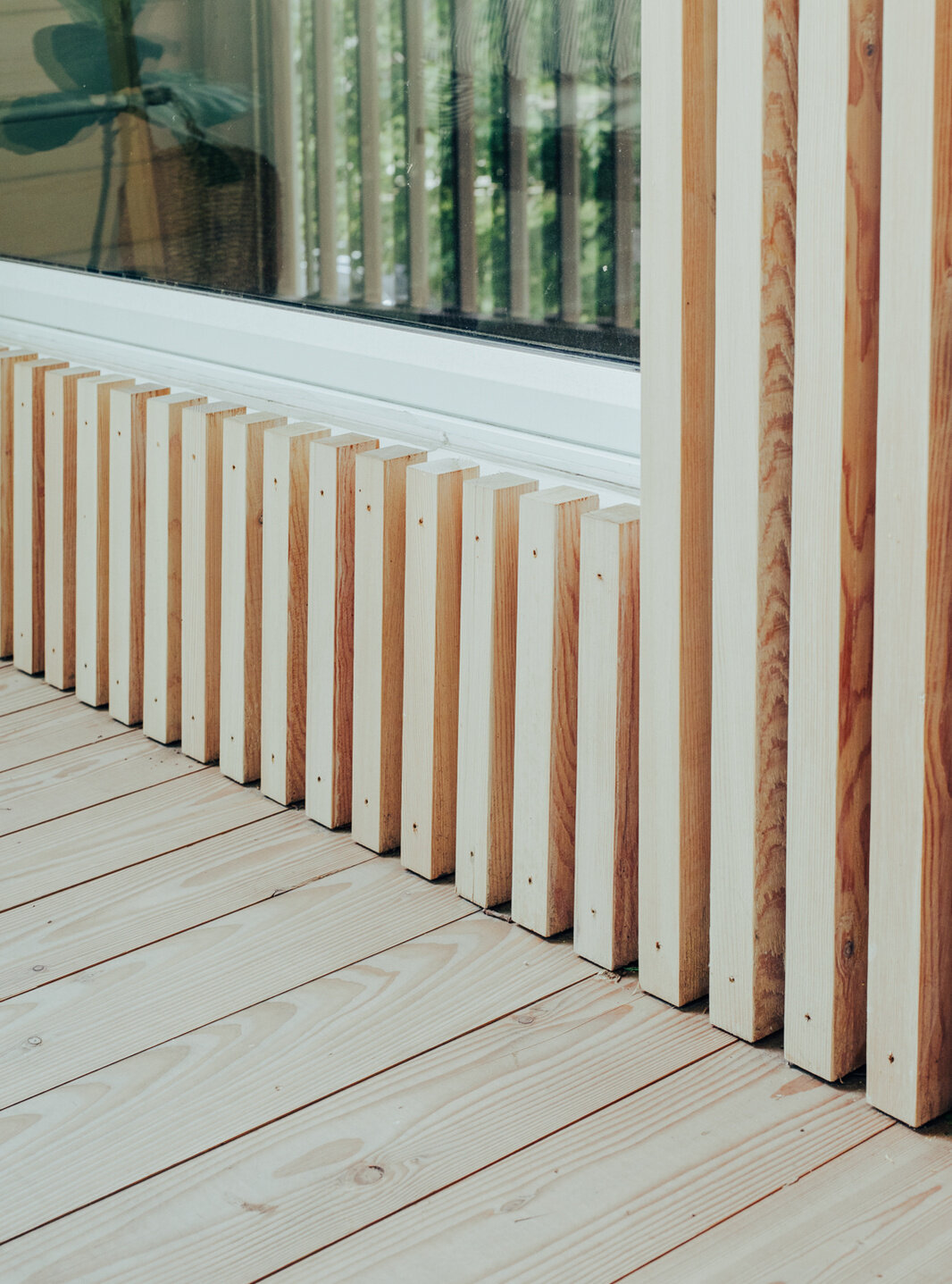 A covered second-floor balcony with timber decking, a wood-lined ceiling, and vertical railings overlooks a mature maple tree at this contemporary Ottawa home.