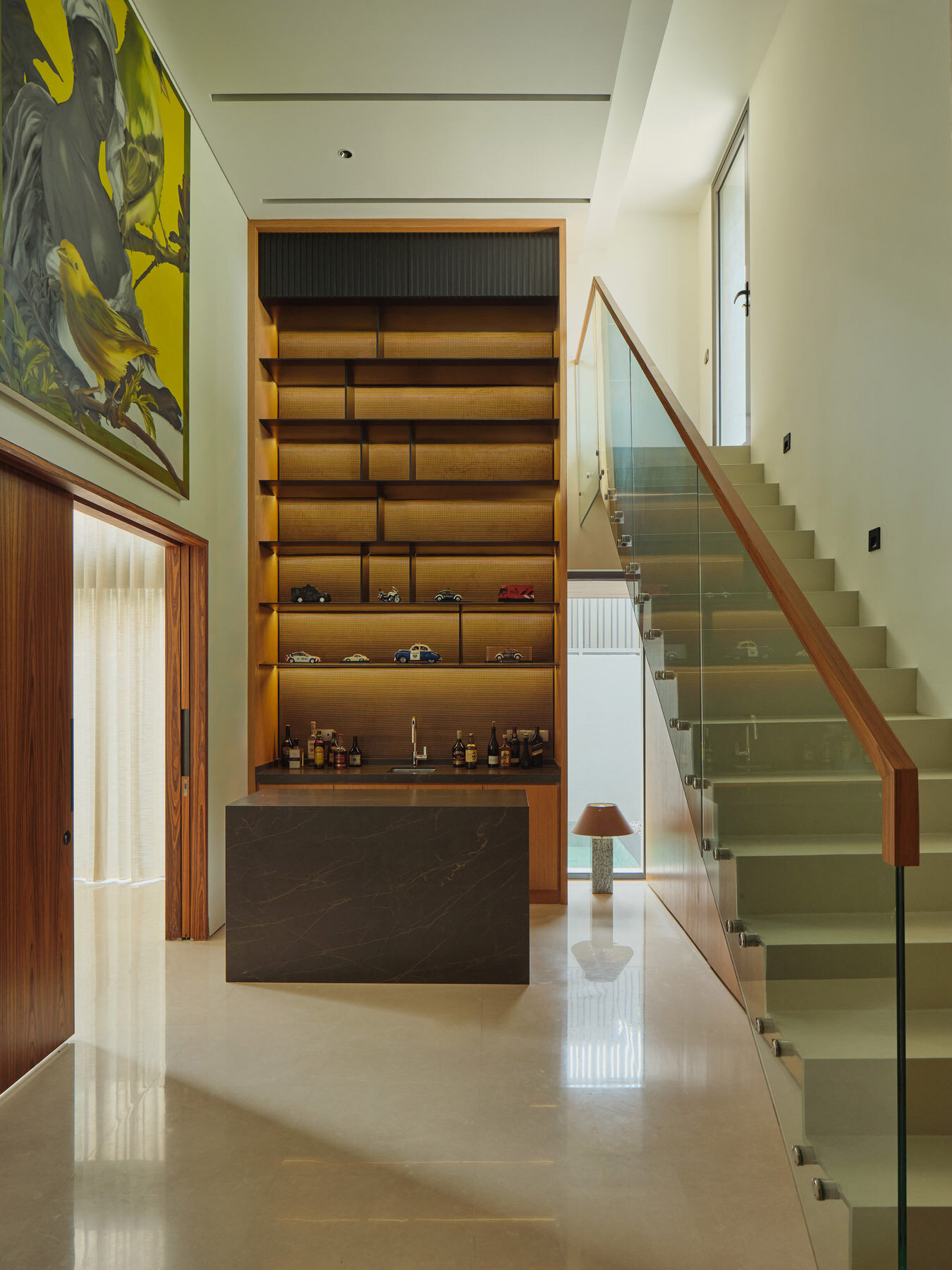 Take a look inside this Singapore home featuring a grand piano, an impressive art collection, and a bar concealed behind timber doors, complete with stone countertops and display shelving.