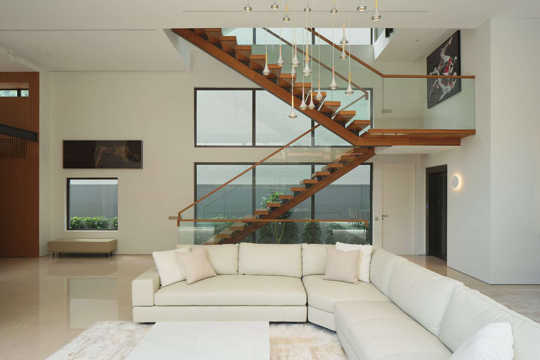 Explore the floating timber staircase in JS-House, featuring open wooden treads, glass balustrades, a central structural support, and skylights that bring daylight into the home.