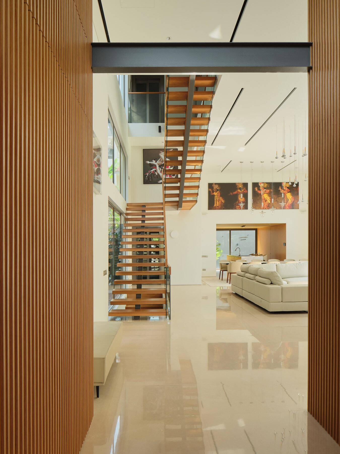 Explore the floating timber staircase in JS-House, featuring open wooden treads, glass balustrades, a central structural support, and skylights that bring daylight into the home.