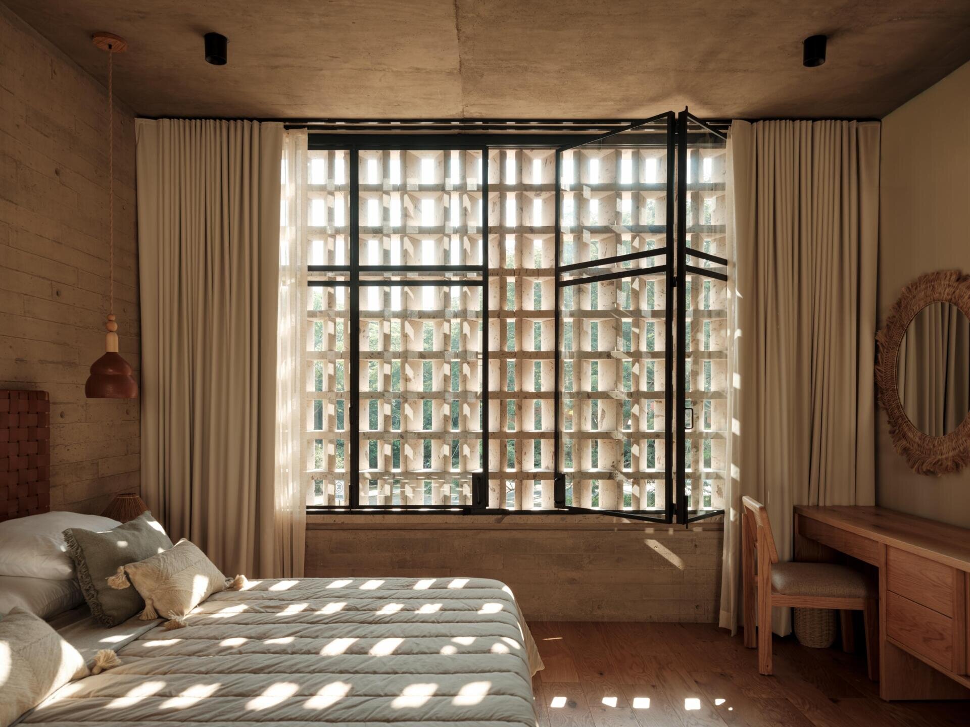 Explore a modern primary bedroom suite featuring a private sitting area, built-in bookshelves, woven sliding doors, a bedroom with geometric breeze-block screens, and a bathroom overlooking a planted courtyard.