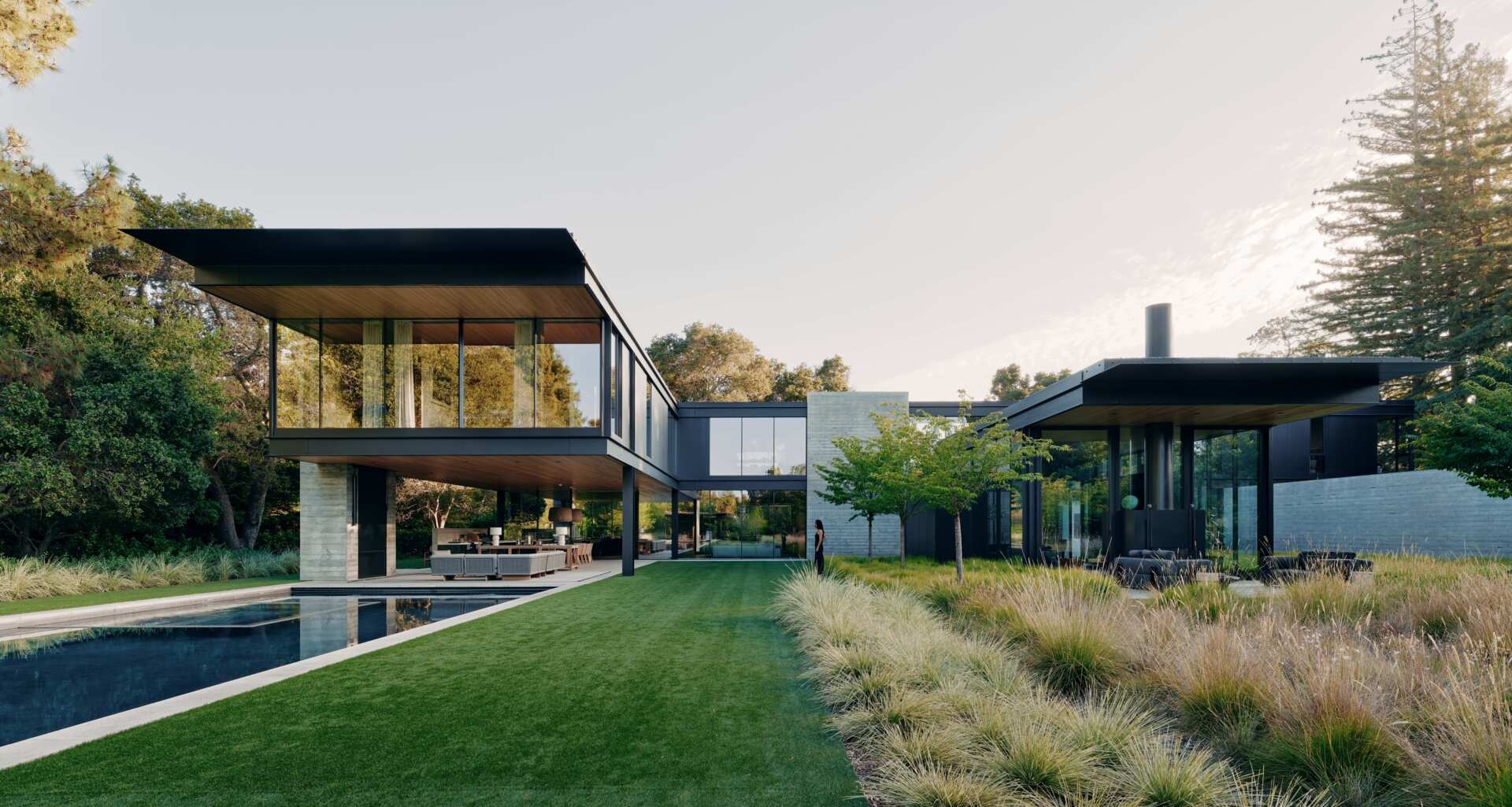 Take a closer look at the modern architecture of this California home by Olson Kundig. Cantilevered upper floors, black metal cladding, board-formed concrete, expansive glass walls, and warm timber ceilings come together in a contemporary house surrounded by gardens.