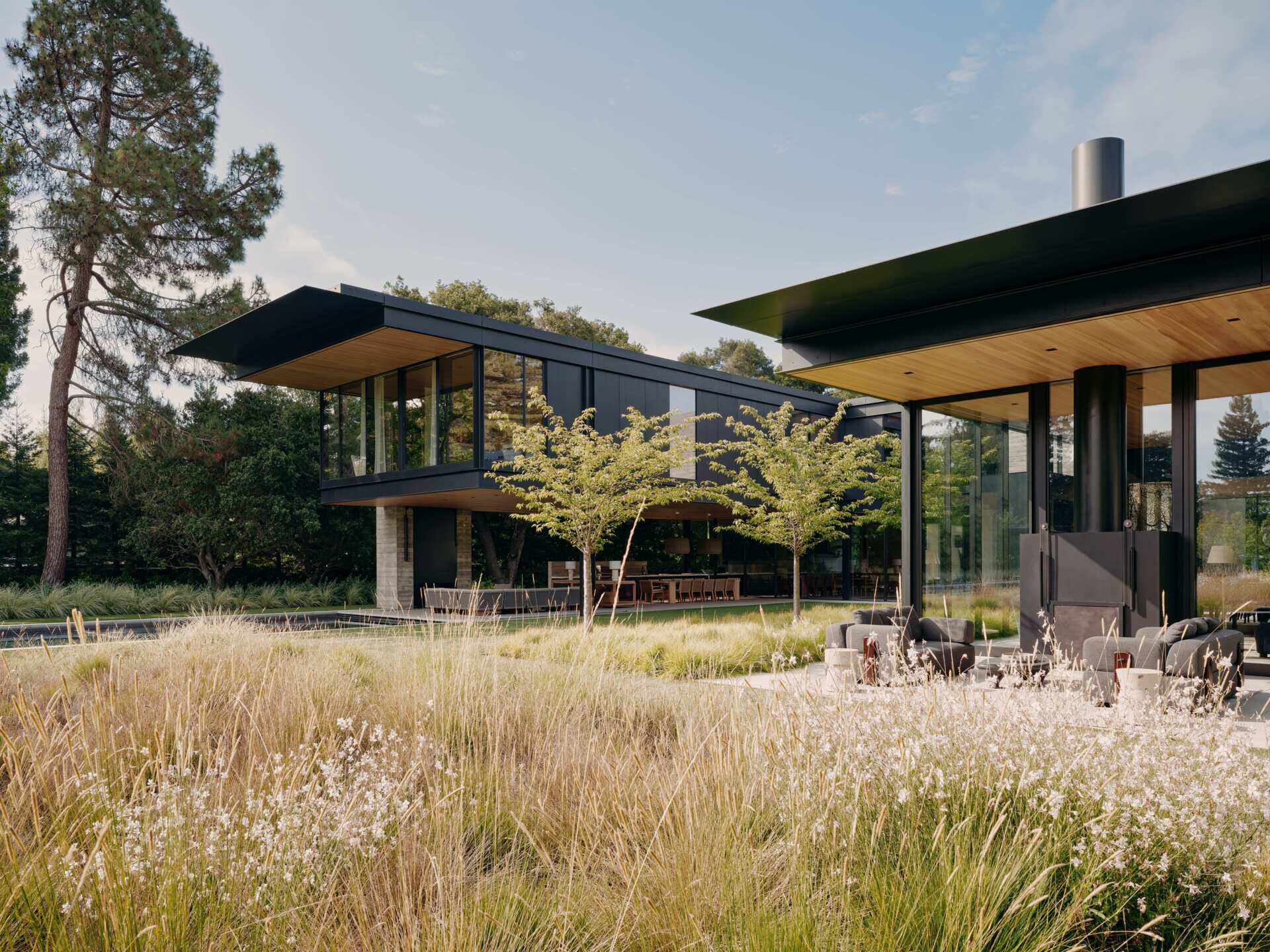 Take a closer look at the modern architecture of this California home by Olson Kundig. Cantilevered upper floors, black metal cladding, board-formed concrete, expansive glass walls, and warm timber ceilings come together in a contemporary house surrounded by gardens.