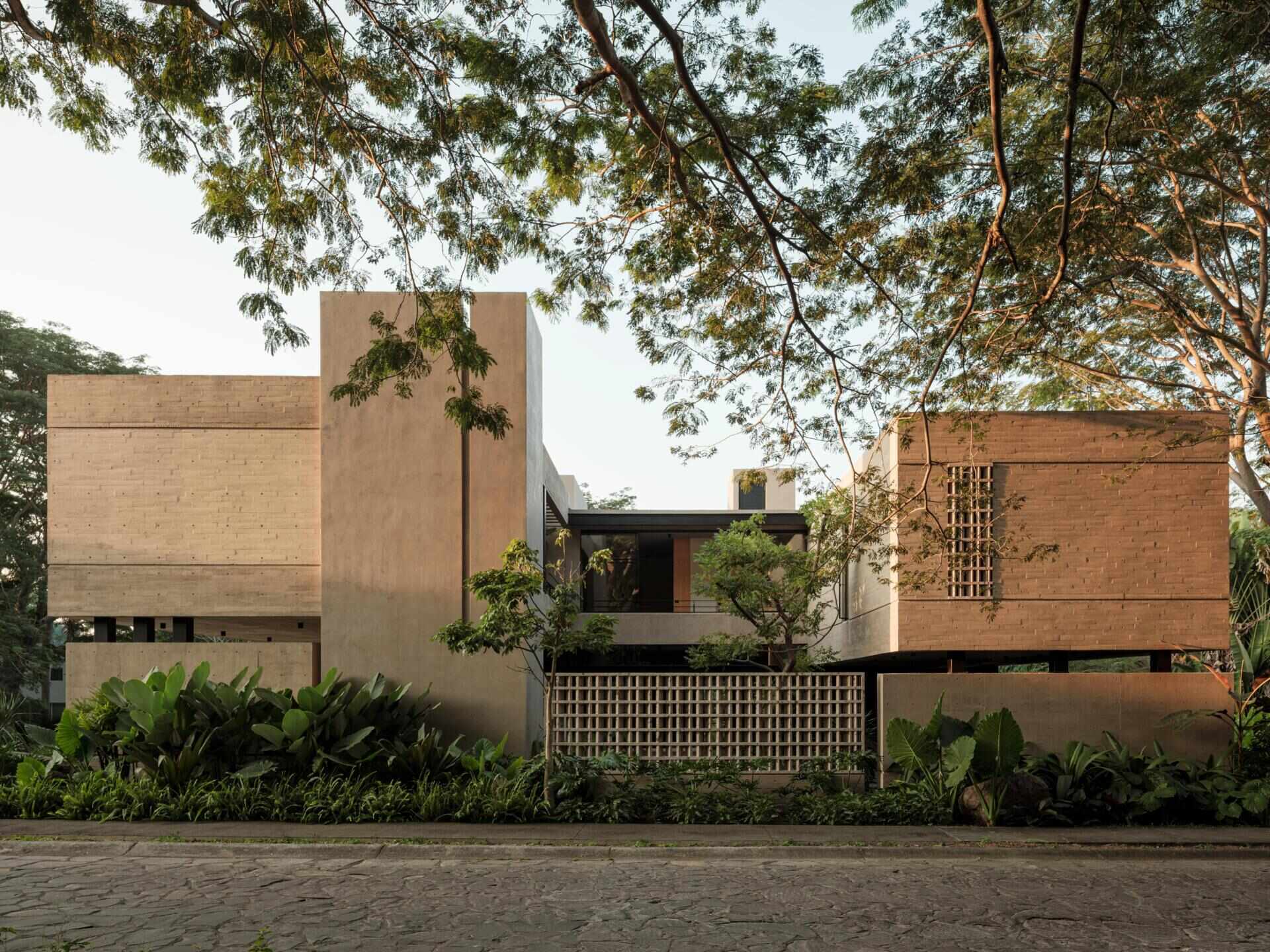 Explore the architecture of Casa Akina in Mexico by Di Frenna arquitectos, featuring board-formed concrete, geometric breeze-block facades, cantilevered volumes, natural stone, and tropical landscaping.