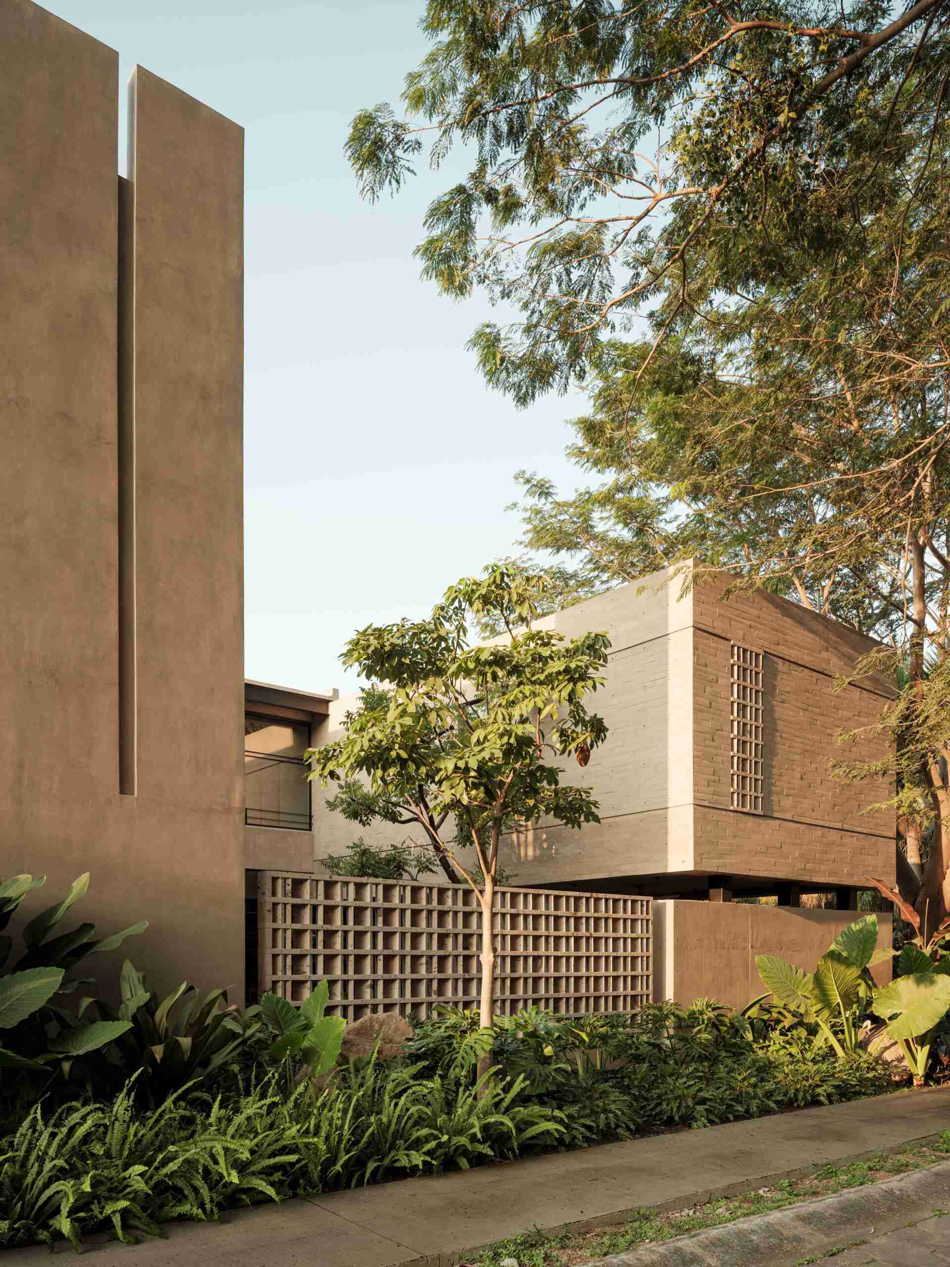 Explore the architecture of Casa Akina in Mexico by Di Frenna arquitectos, featuring board-formed concrete, geometric breeze-block facades, cantilevered volumes, natural stone, and tropical landscaping.