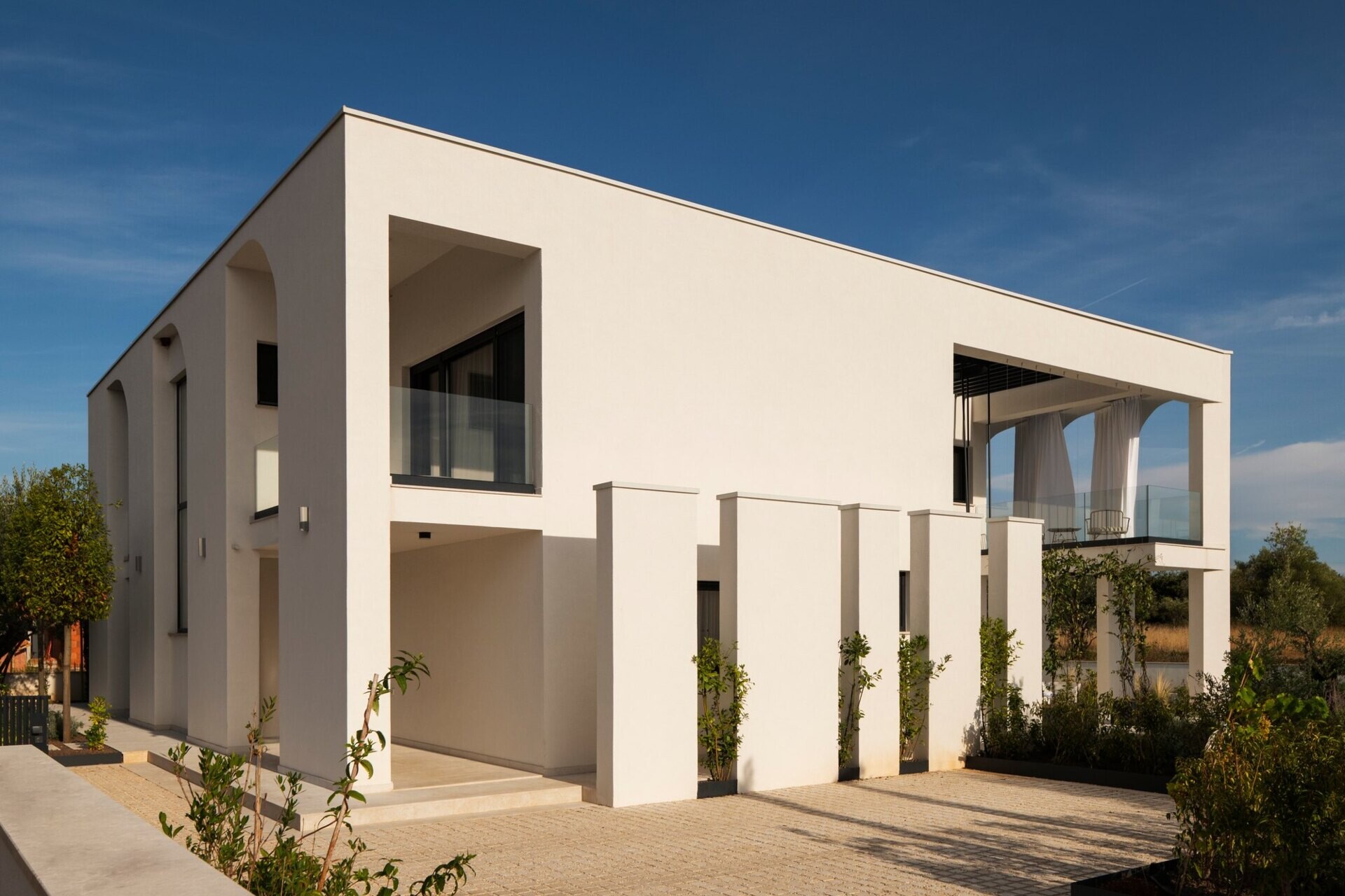 Discover the architecture of Arc House in Istria, Croatia, by Ivan Gavran Vlahovic. This contemporary white villa features geometric half-arches, symmetrical façades, recessed balconies and minimalist Mediterranean architecture inspired by classical country houses.