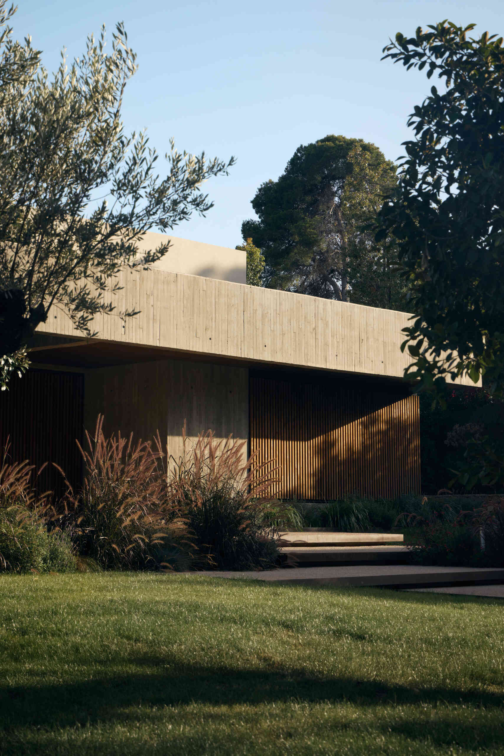 This modern concrete home by Viruta Lab in Valencia, Spain, features an L-shaped floor plan, board-marked concrete walls, horizontal architecture, and landscaped gardens.
