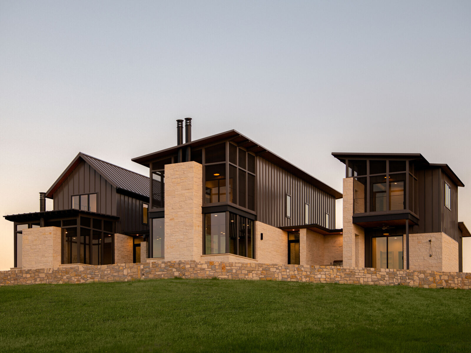 Two modern Texas homes by Jeff Garnett Architect combine native limestone walls, dark metal cladding, and contrasting rooflines.