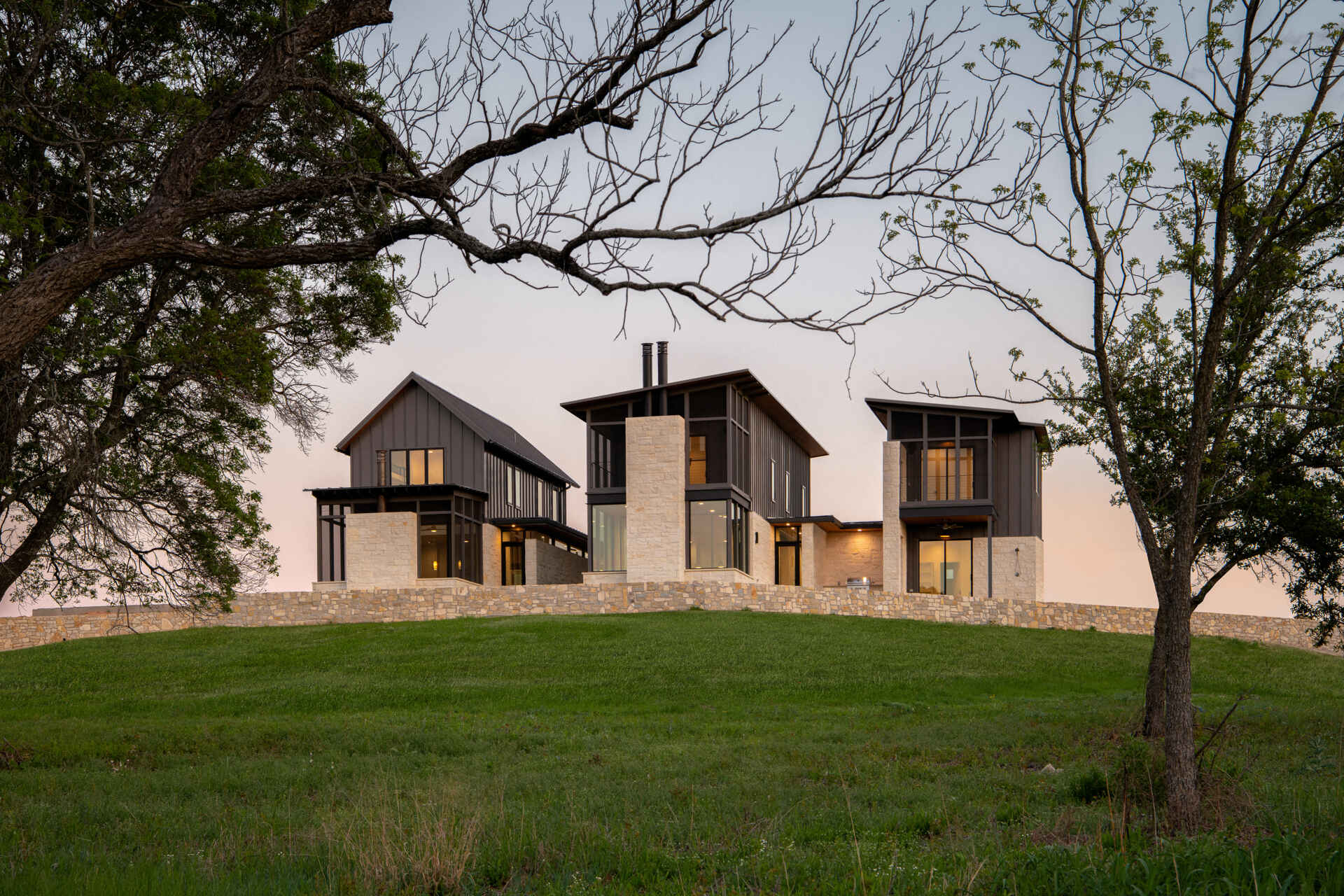 Two modern Texas homes by Jeff Garnett Architect combine native limestone walls, dark metal cladding, and contrasting rooflines.