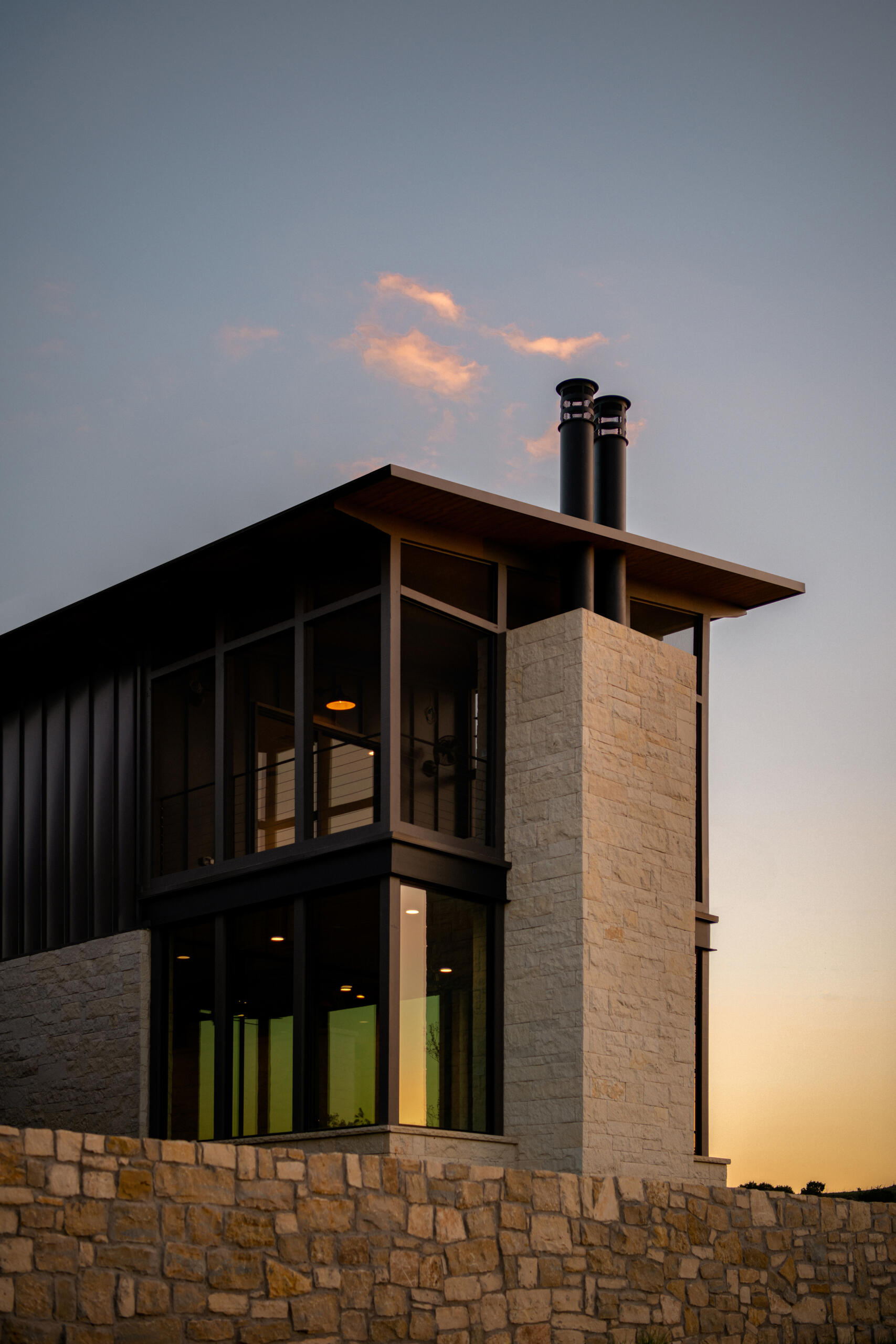Two modern Texas homes by Jeff Garnett Architect combine native limestone walls, dark metal cladding, and contrasting rooflines.