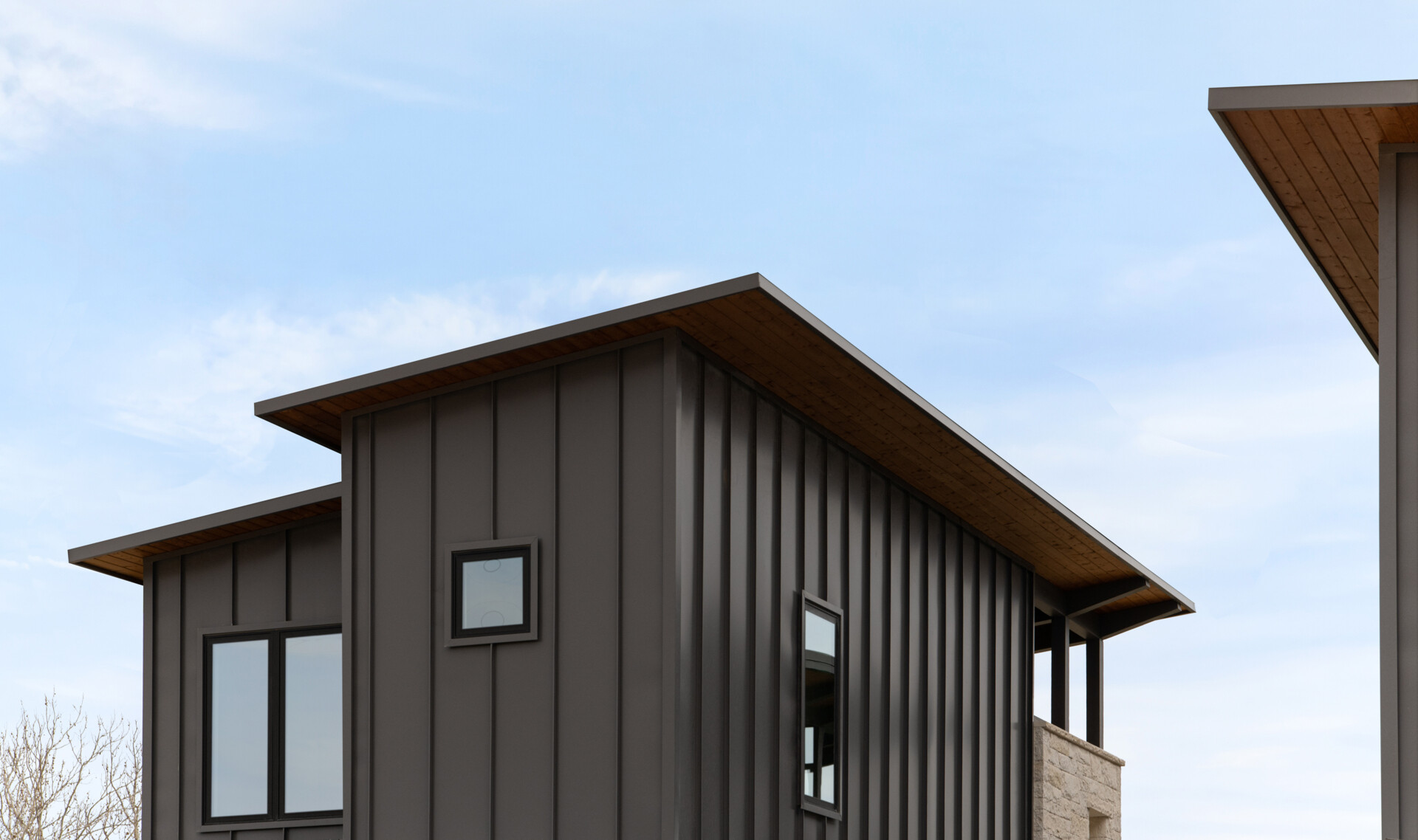Two modern Texas homes by Jeff Garnett Architect combine native limestone walls, dark metal cladding, and contrasting rooflines.