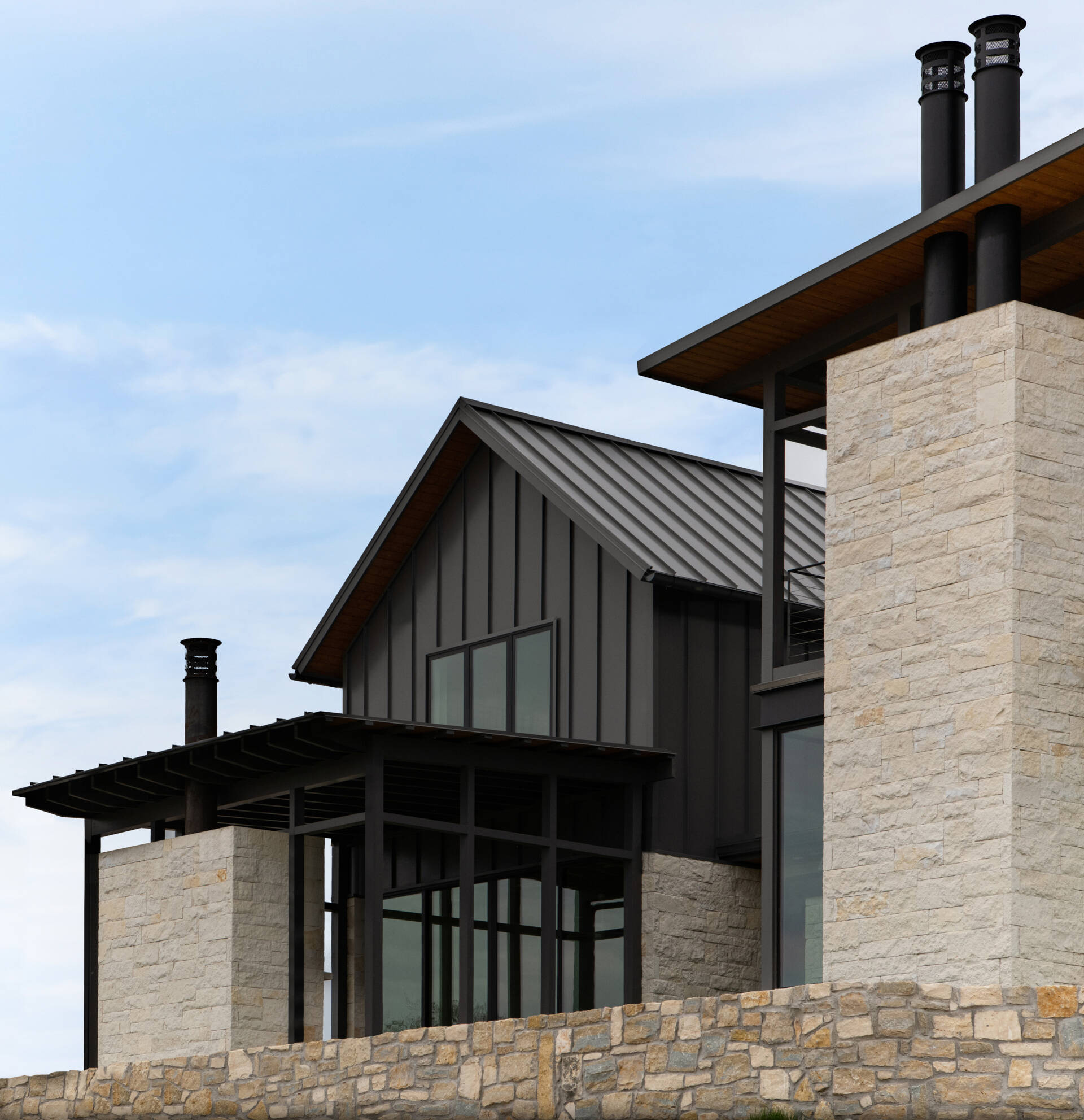 Two modern Texas homes by Jeff Garnett Architect combine native limestone walls, dark metal cladding, and contrasting rooflines.