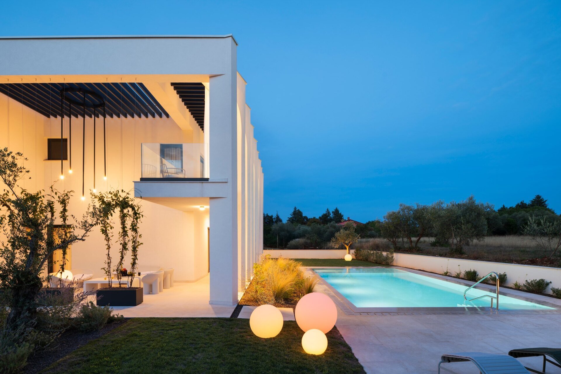 Explore the swimming pool and south-facing façade of Arc House, a modern villa in Istria, Croatia. A rectangular pool, sculptural concrete arches, covered balconies and Mediterranean landscaping create an impressive contemporary outdoor living area.