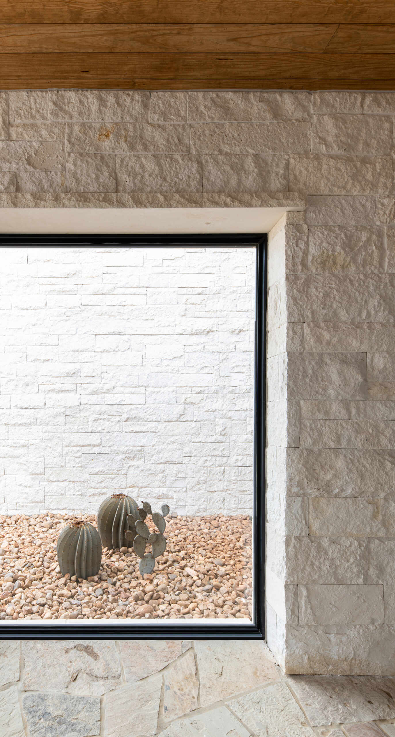 Small windows framed by limestone create unexpected architectural details, including a view into a miniature cactus garden.