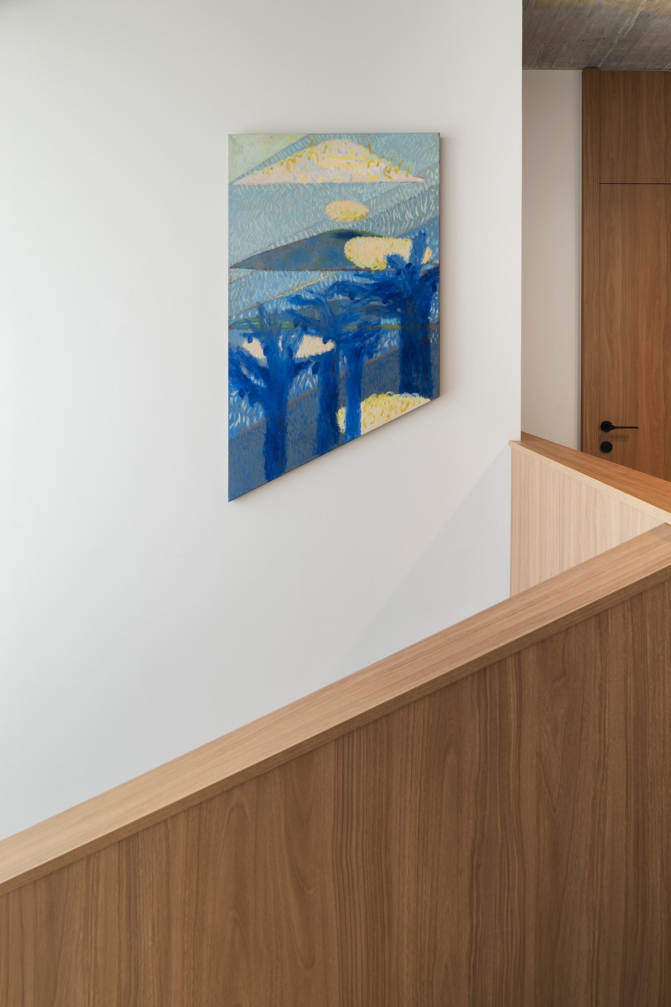 Discover the modern staircase at Arc House, a contemporary Croatian villa, featuring pale green stairs, timber balustrades, exposed concrete ceilings, black architectural lighting and colourful art along the upper landing.