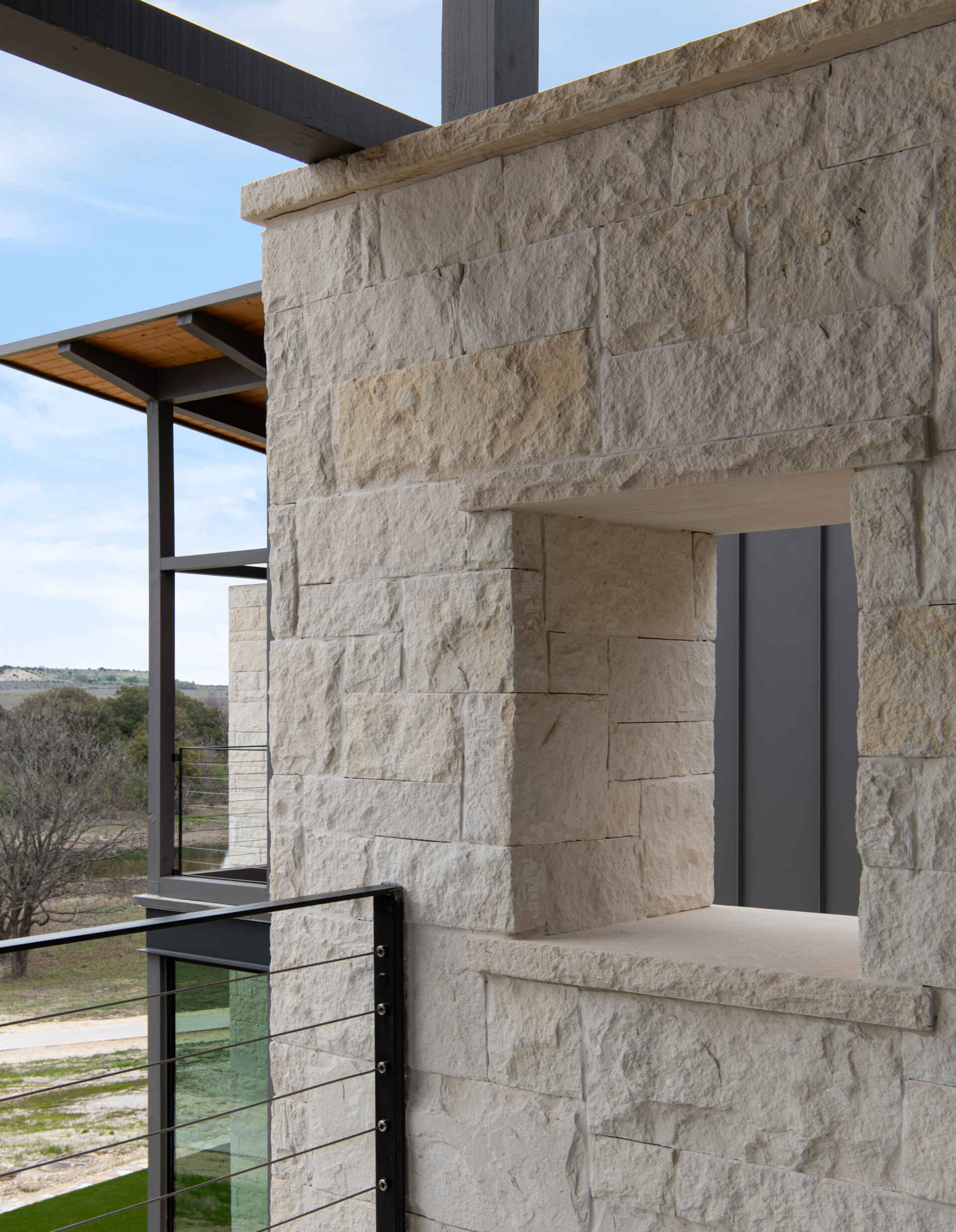 Two modern Texas homes by Jeff Garnett Architect combine native limestone walls, dark metal cladding, and contrasting rooflines.