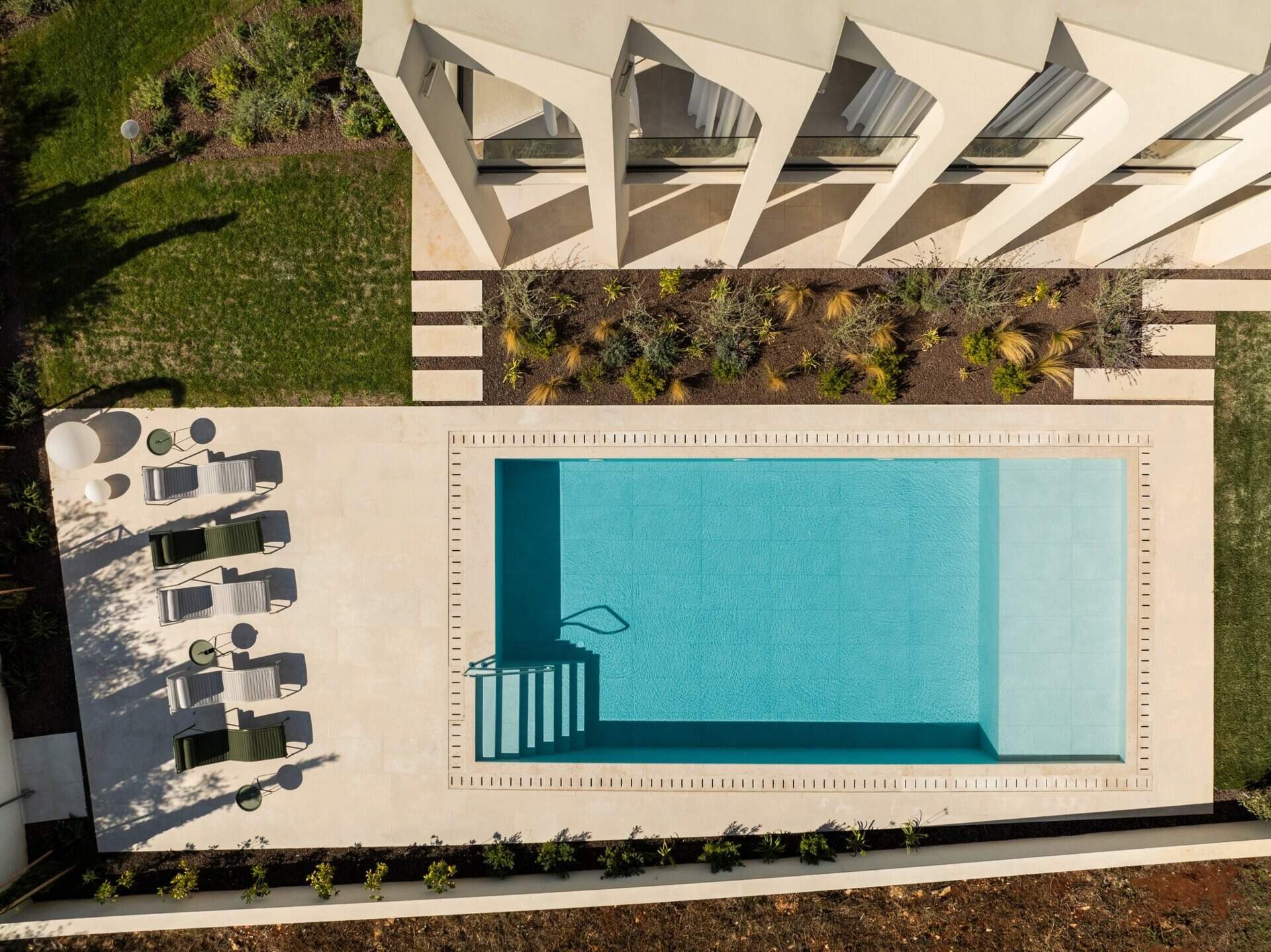 Explore the swimming pool and south-facing façade of Arc House, a modern villa in Istria, Croatia. A rectangular pool, sculptural concrete arches, covered balconies and Mediterranean landscaping create an impressive contemporary outdoor living area.