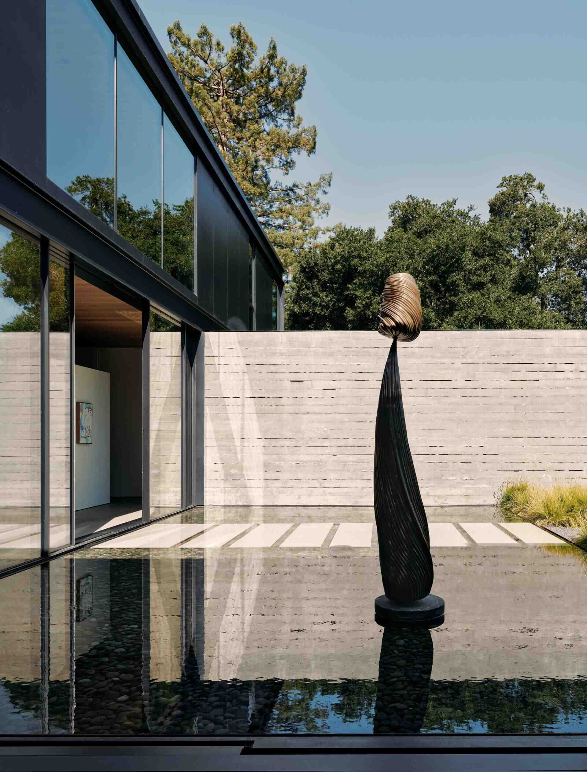 Discover modern architectural water features at this California home by Olson Kundig. Shallow reflecting pools, sculptural artwork, concrete courtyard walls, and floating stepping stones create beautiful outdoor spaces between the home's contemporary buildings.