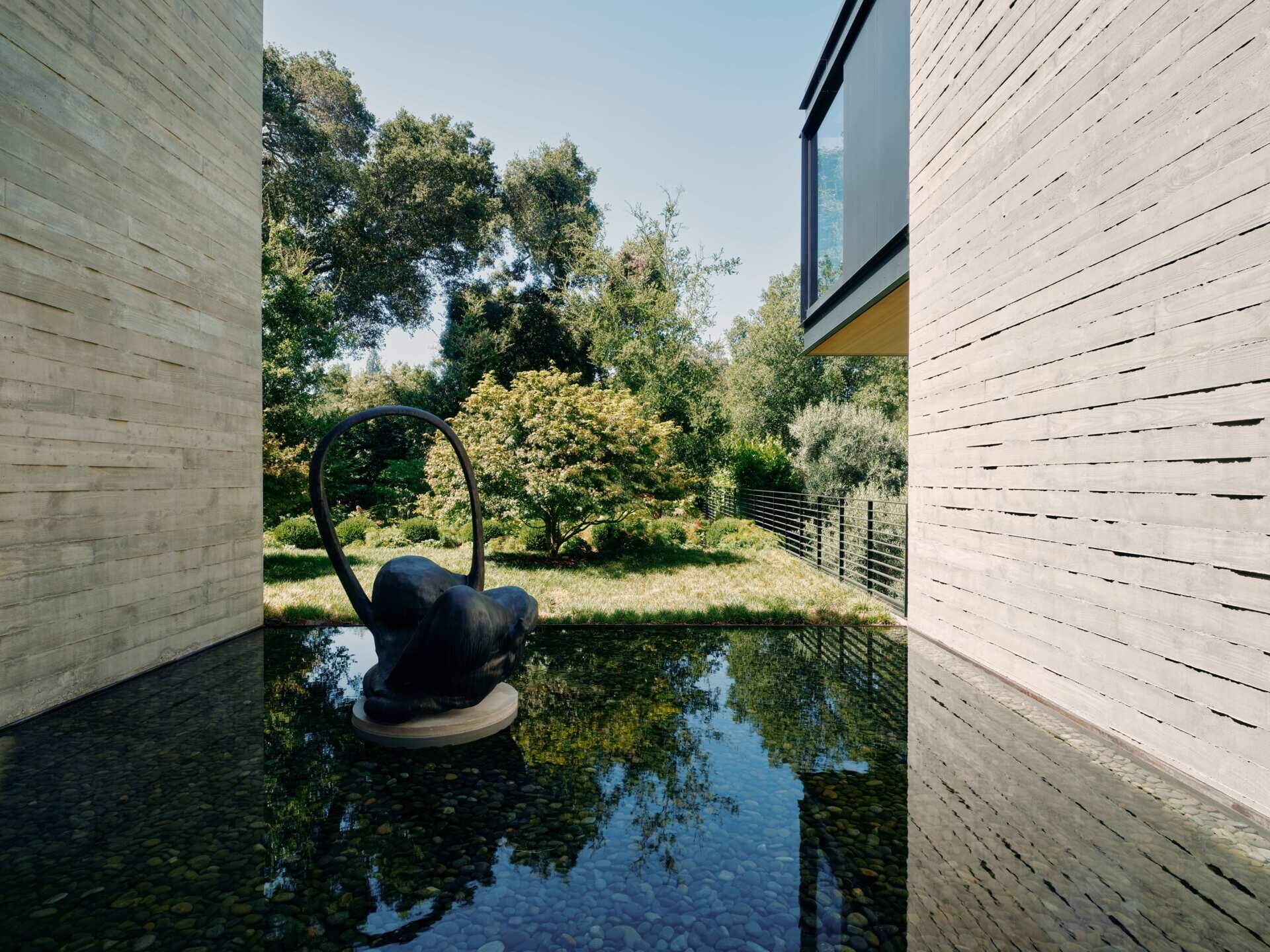 Discover modern architectural water features at this California home by Olson Kundig. Shallow reflecting pools, sculptural artwork, concrete courtyard walls, and floating stepping stones create beautiful outdoor spaces between the home's contemporary buildings.