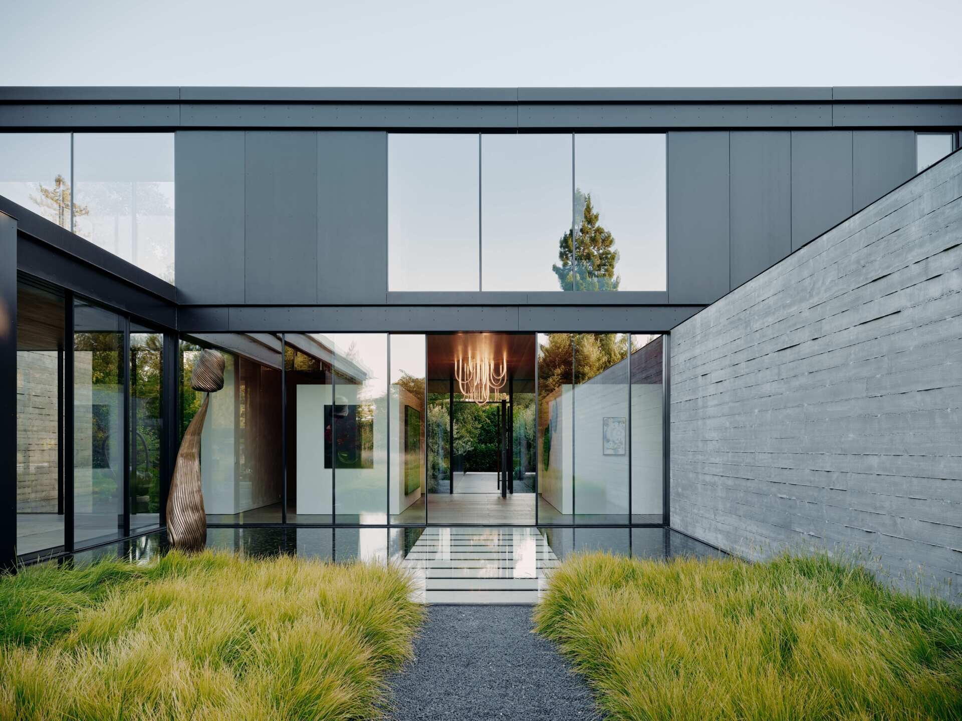 Discover modern architectural water features at this California home by Olson Kundig. Shallow reflecting pools, sculptural artwork, concrete courtyard walls, and floating stepping stones create beautiful outdoor spaces between the home's contemporary buildings.