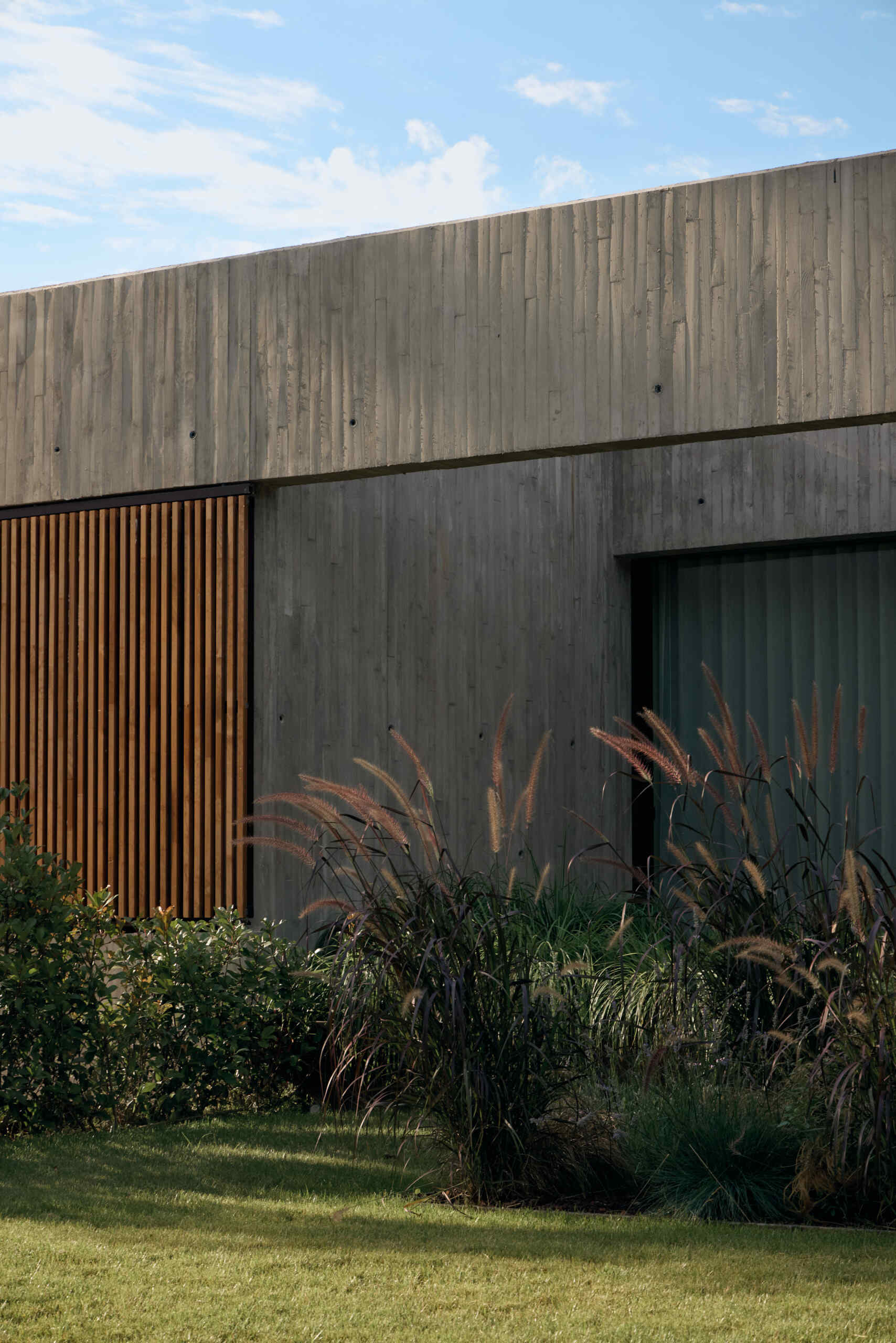Discover how sliding timber screens add warmth, privacy, and natural sun protection to this modern concrete house in Spain. An inspiring exterior design by Viruta Lab.