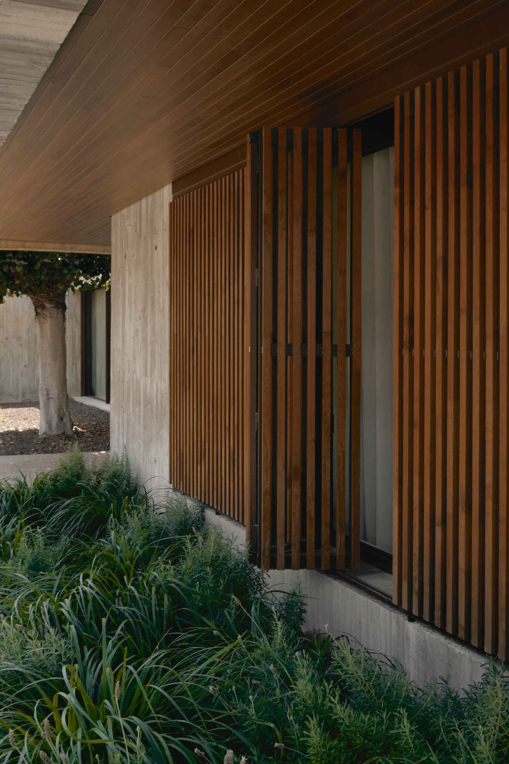 Discover how sliding timber screens add warmth, privacy, and natural sun protection to this modern concrete house in Spain. An inspiring exterior design by Viruta Lab.