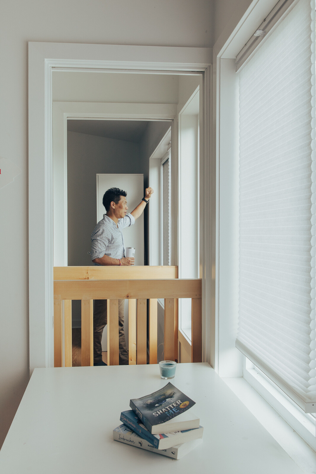 Explore a bright upstairs bedroom with white walls, warm wooden floors, an exposed ceiling beam, colorful artwork, and space-saving pocket doors in a renovated family home.