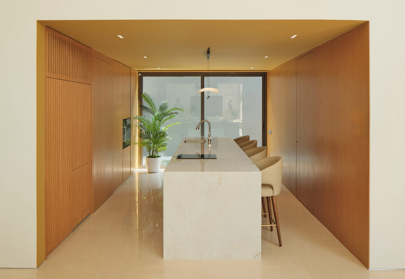Discover a contemporary dining room and kitchen in Singapore, featuring a long marble dining table, upholstered seating, timber cabinetry, and a minimalist stone kitchen island.