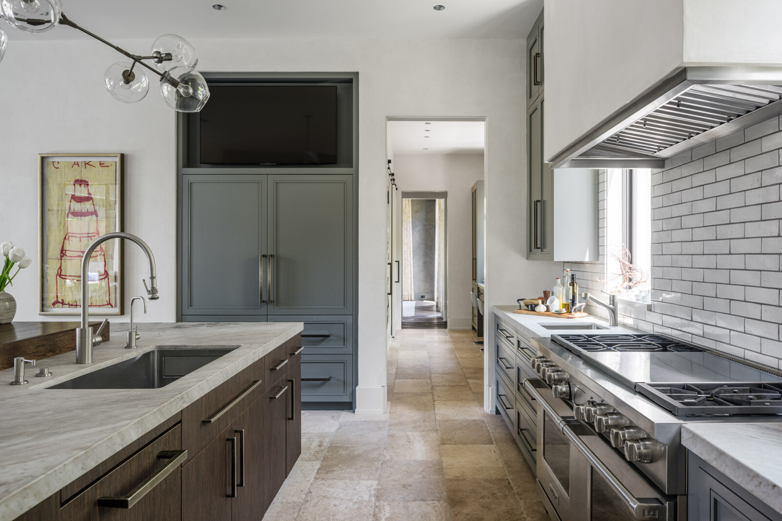 A contemporary kitchen with gray cabinets, white subway tile, stone countertops, a dark wood island, rustic wood breakfast bar, and modern glass globe pendant lighting.