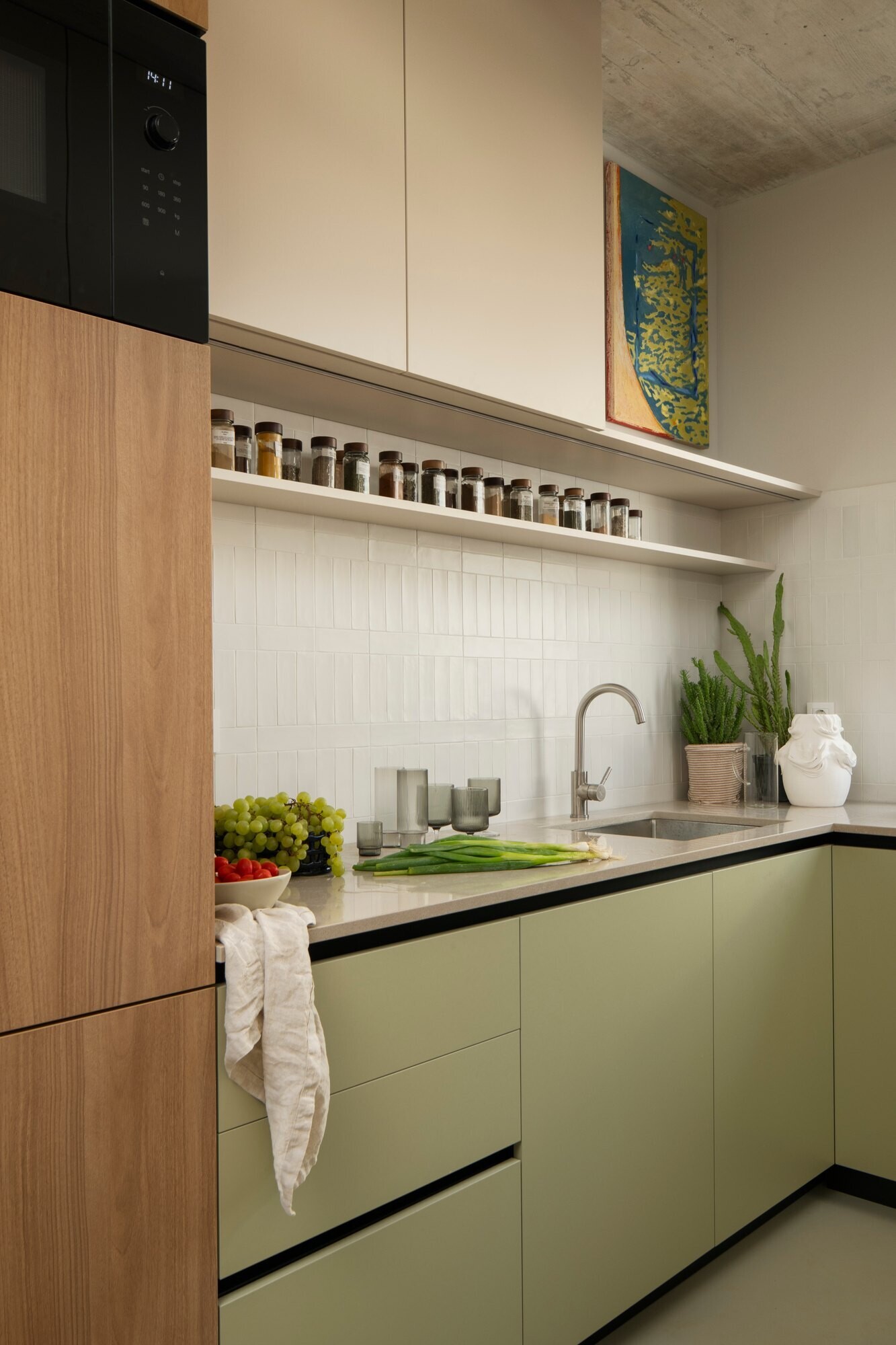Get inspired by the kitchen at Arc House in Istria, featuring natural wood cabinetry, sage-green kitchen cabinets, a stone breakfast bar, cobalt-blue stools, open shelving and dark green pendant lights.