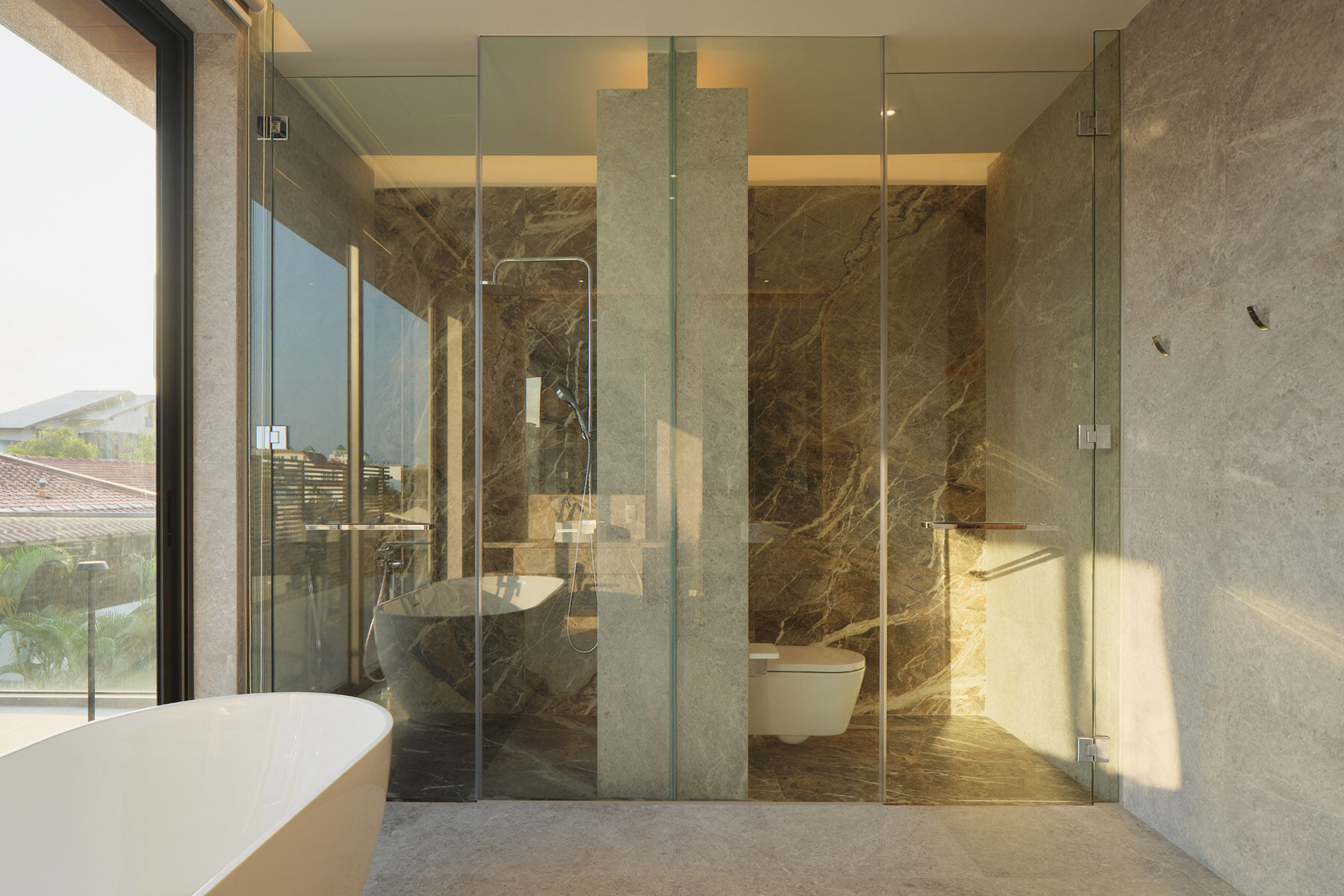 Explore the primary bathroom of this Singapore home, featuring a floating marble double vanity, vessel sinks, a freestanding bathtub, glass shower enclosures, and natural stone finishes.