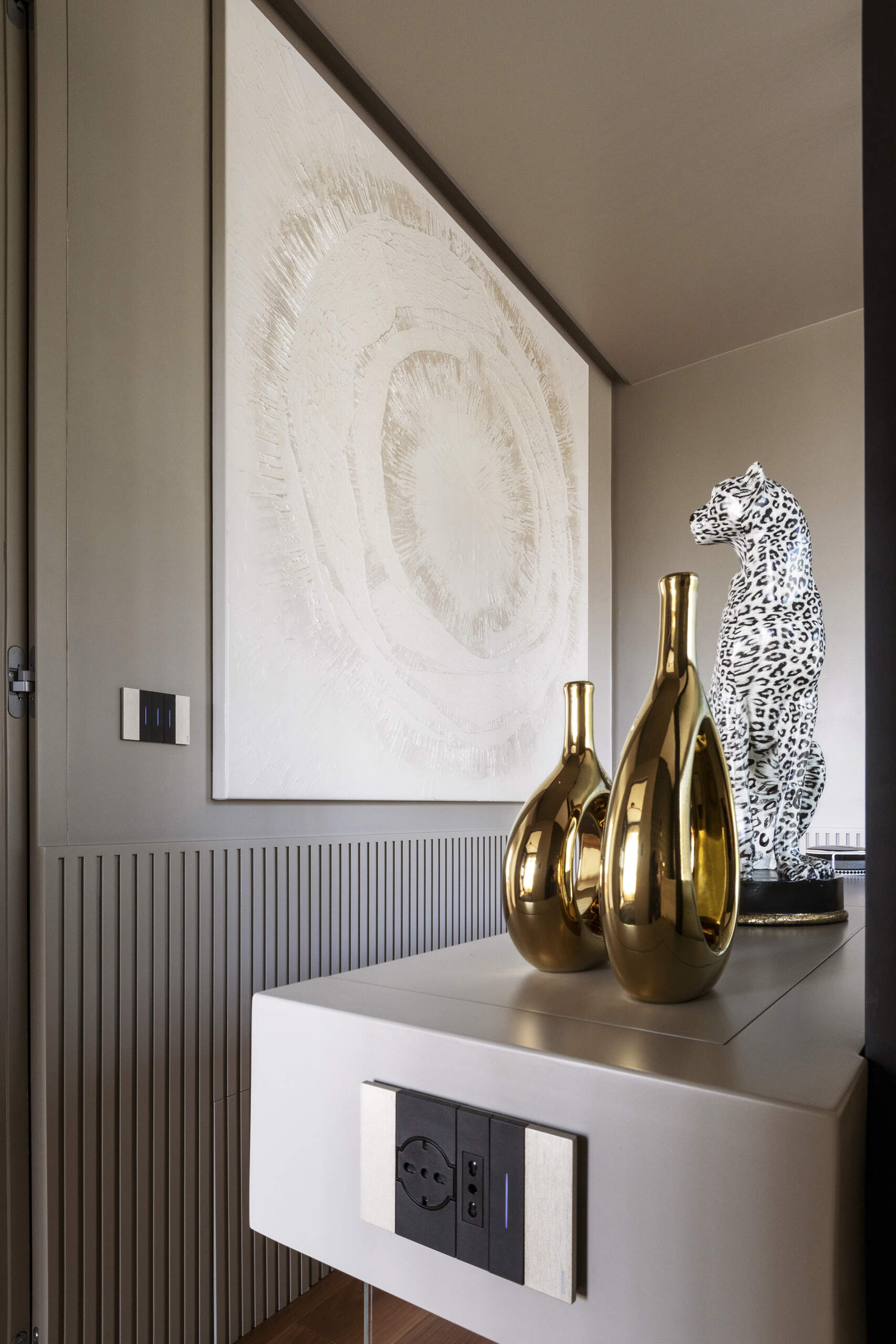 This primary bedroom features Art Deco wallpaper, a white upholstered headboard, black pendant lights, and a custom dressing counter with an arched glass partition.
