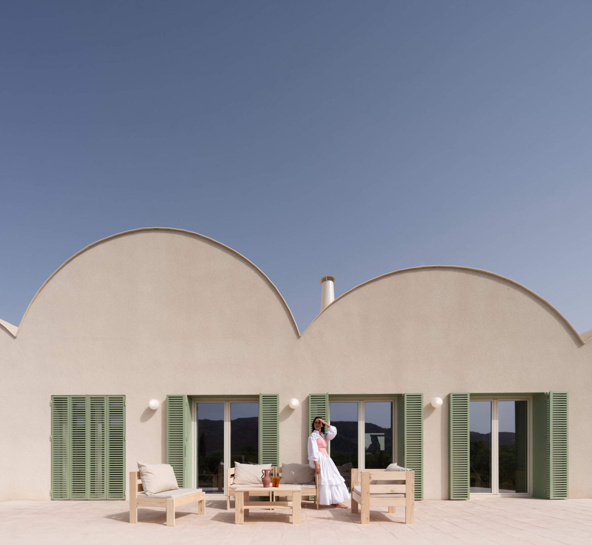 Curved Catalan vaulted roofs, a pale cork exterior, and green Mediterranean shutters give this contemporary home its unique character.