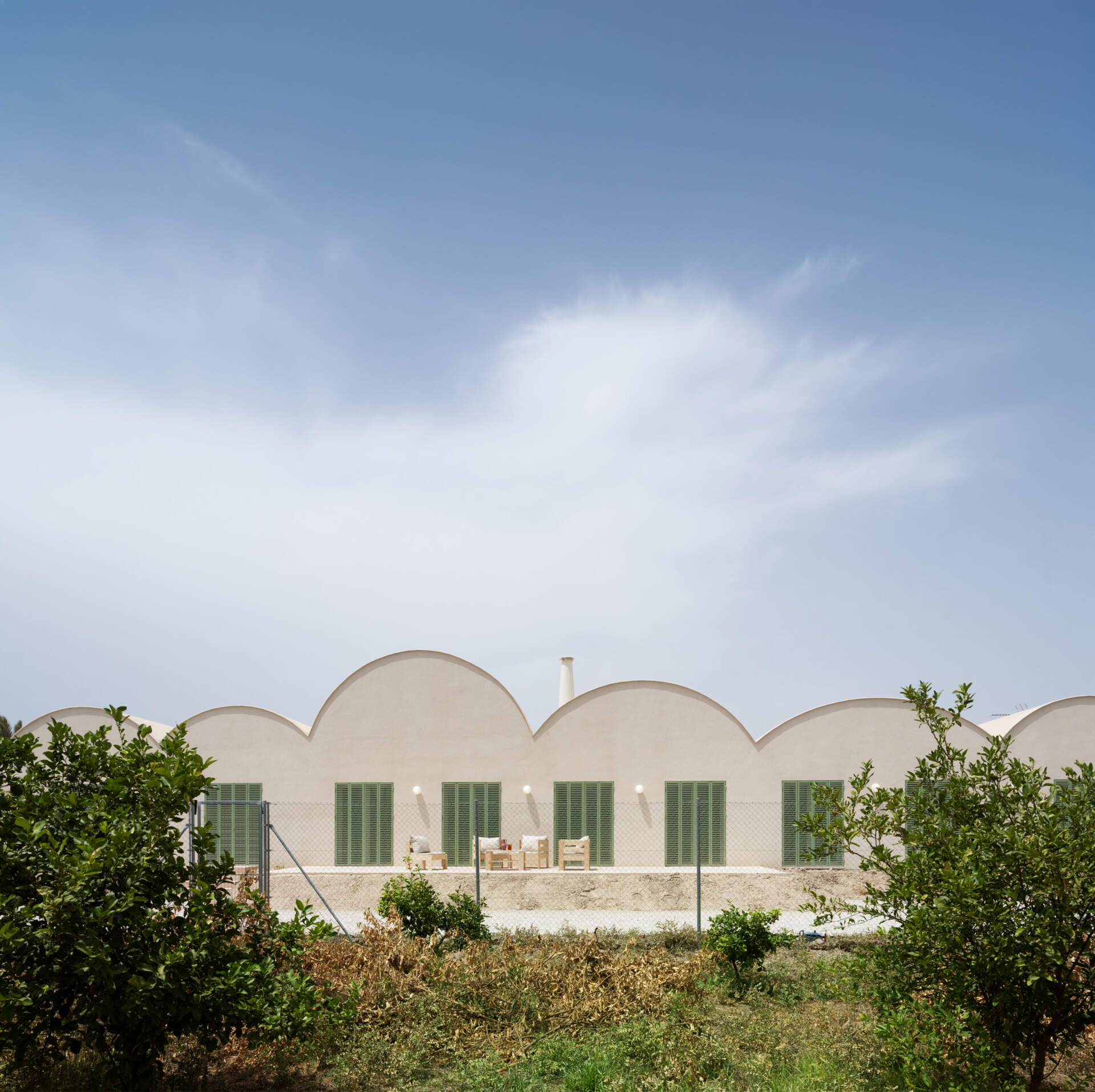 Curved Catalan vaulted roofs, a pale cork exterior, and green Mediterranean shutters give this contemporary home its unique character.
