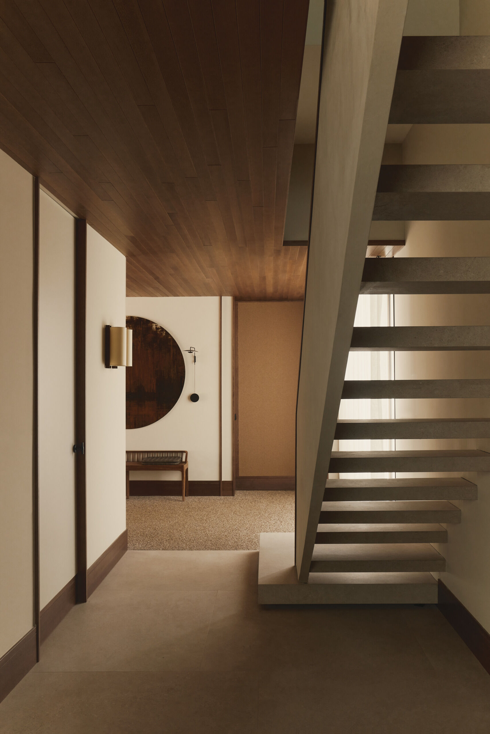 Explore a modern floating-style staircase with cantilevered concrete steps, open risers, minimalist detailing, and an oversized platform step in a contemporary Spanish home.