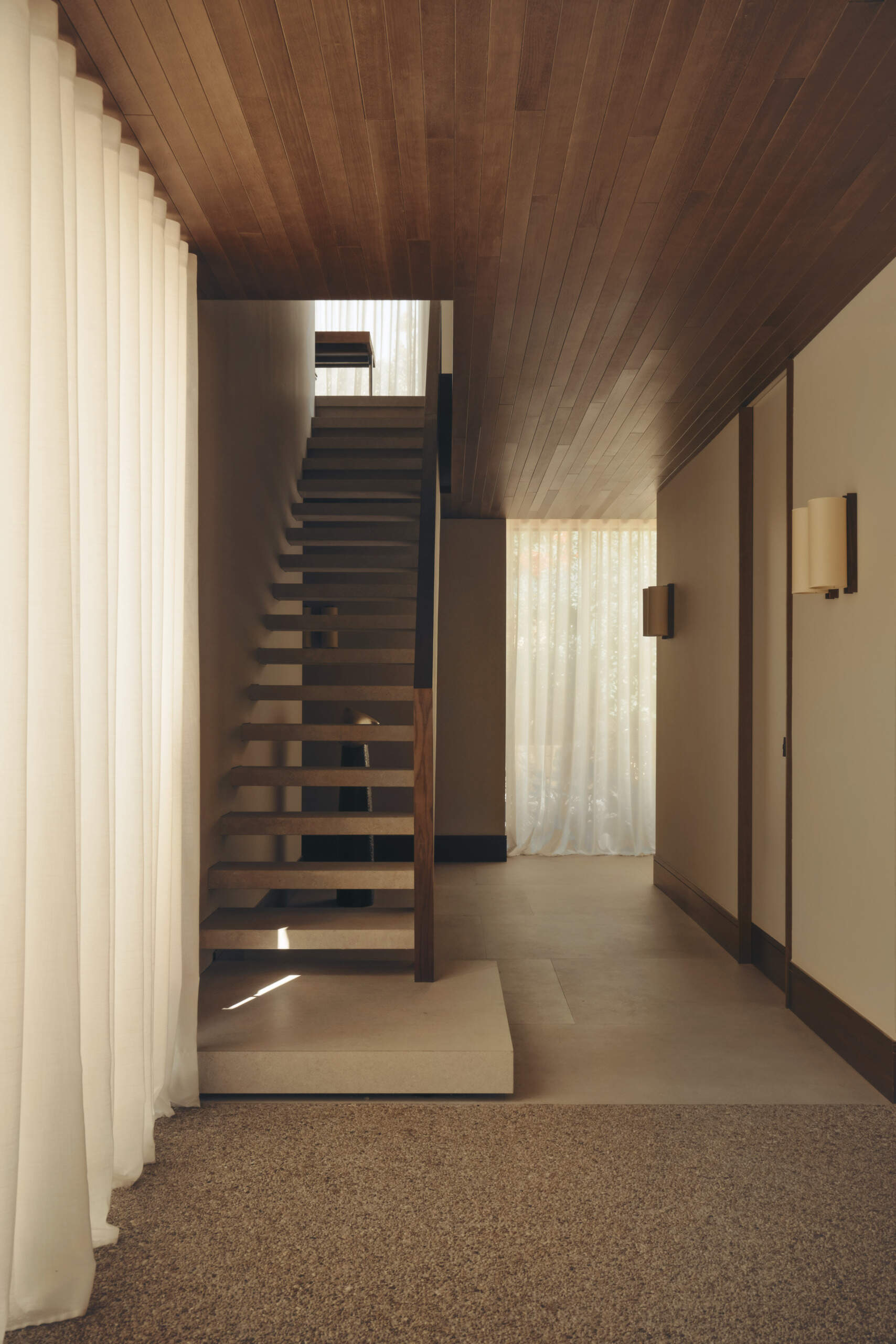 Explore a modern floating-style staircase with cantilevered concrete steps, open risers, minimalist detailing, and an oversized platform step in a contemporary Spanish home.