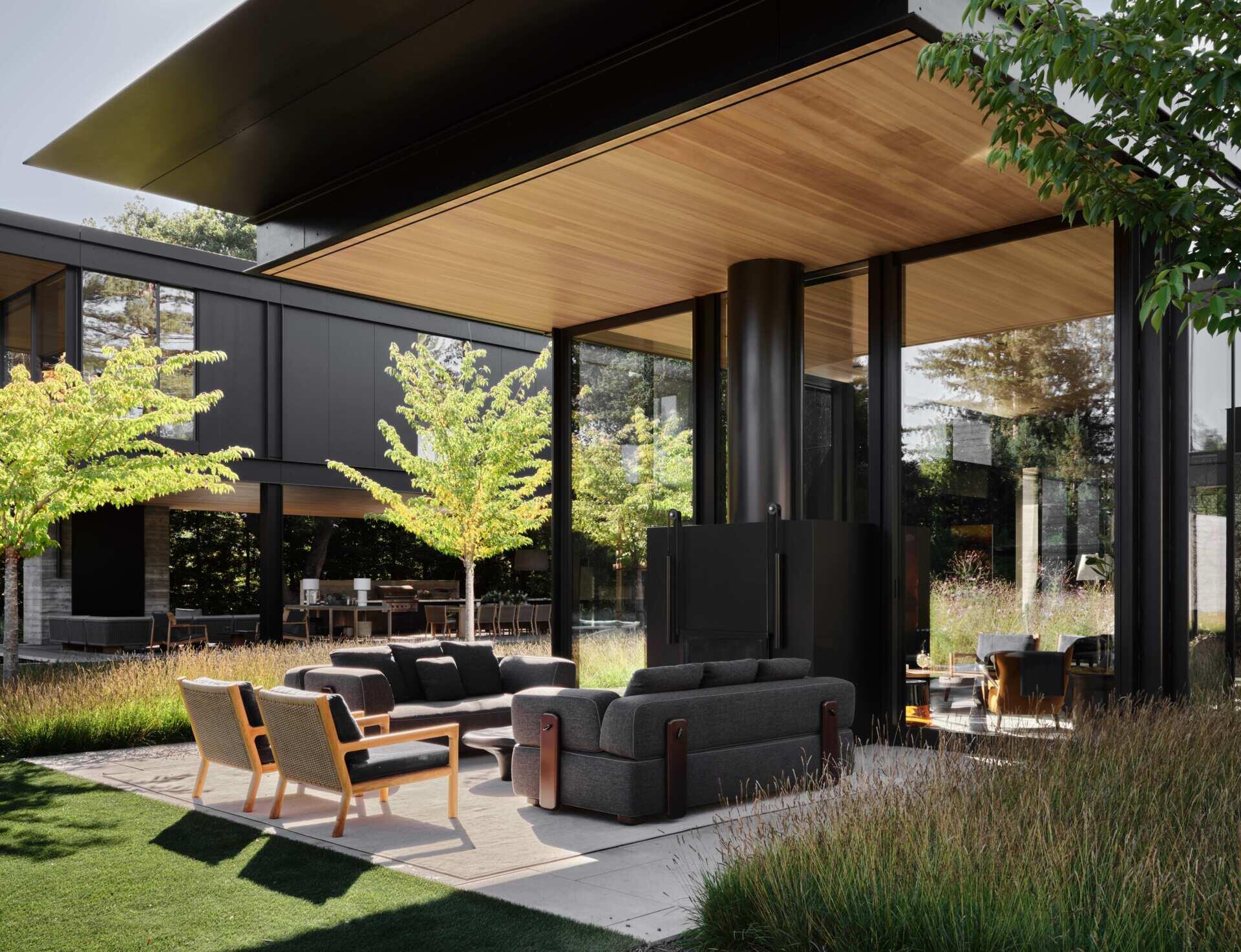 Outside, charcoal upholstered sofas and timber-framed lounge chairs, creating a natural continuation of the indoor space.
