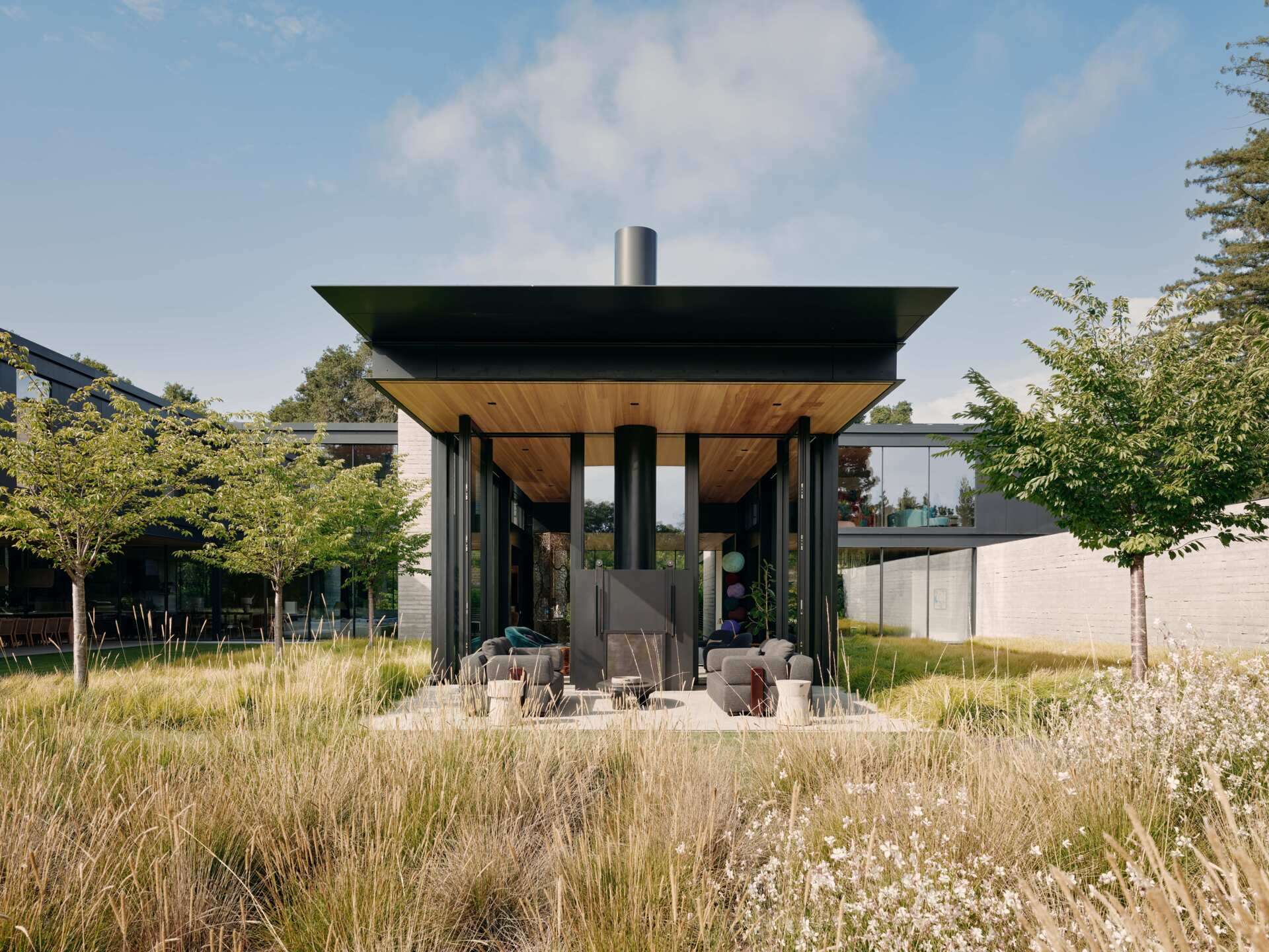 Outside, charcoal upholstered sofas and timber-framed lounge chairs, creating a natural continuation of the indoor space.