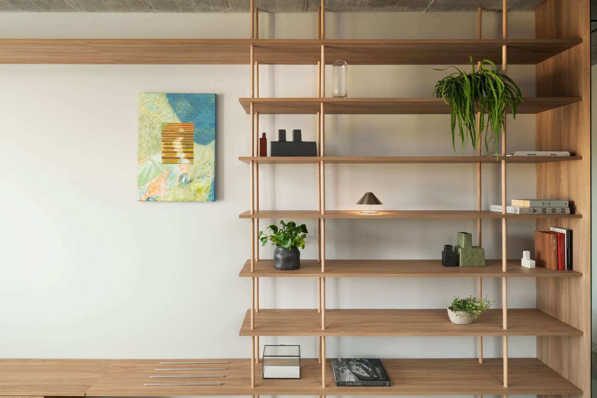 Tour the primary bedroom suite at Arc House in Croatia, featuring a timber platform bed, blue and green bedding, built-in wardrobes, a private sitting area, open wooden shelving and access to a covered terrace.