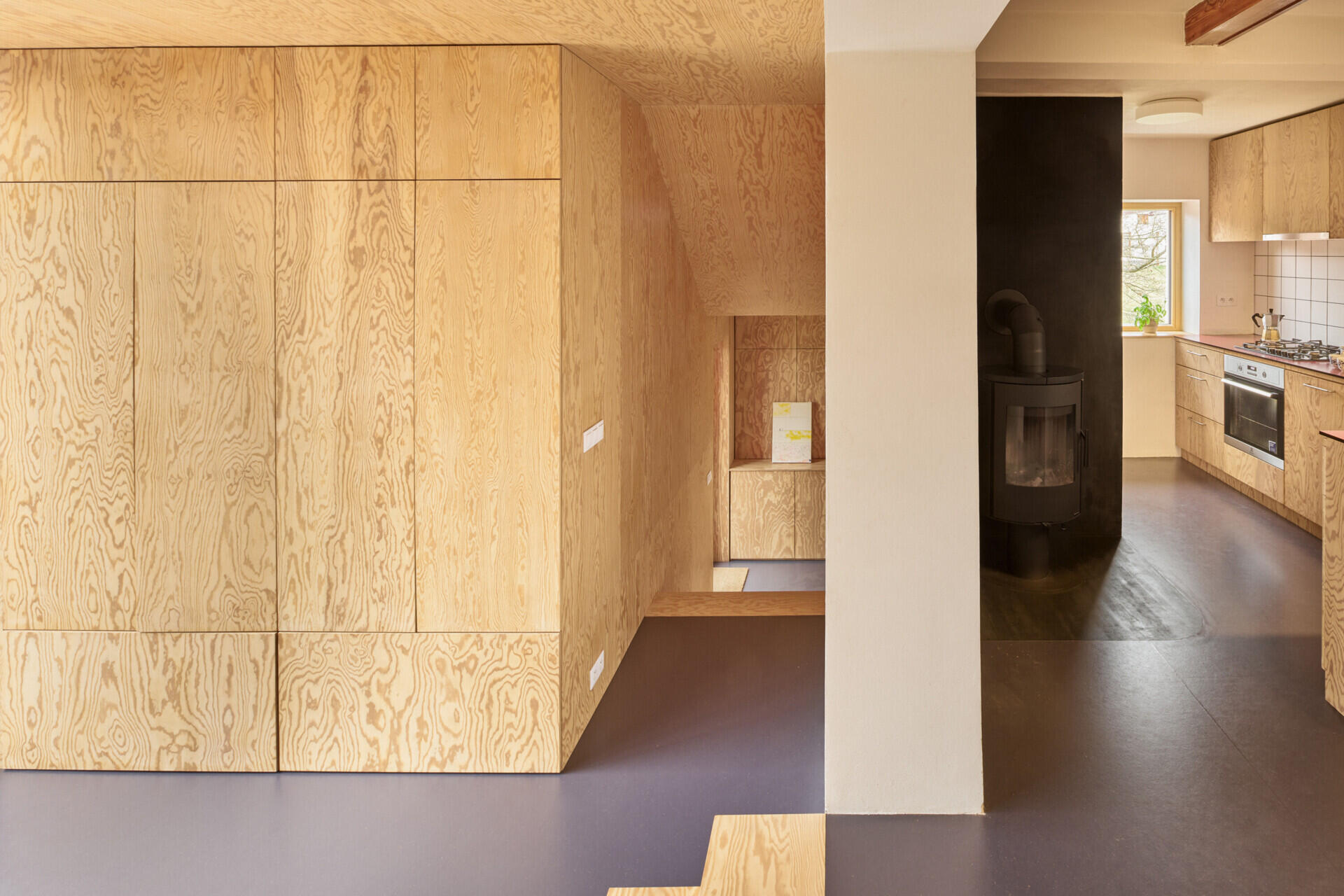 Inside the extension by Facha architekti, pine plywood wraps the entryway and hallway, with built-in storage and custom furniture helping make the most of the compact family home in Ne?ín, Czech Republic.