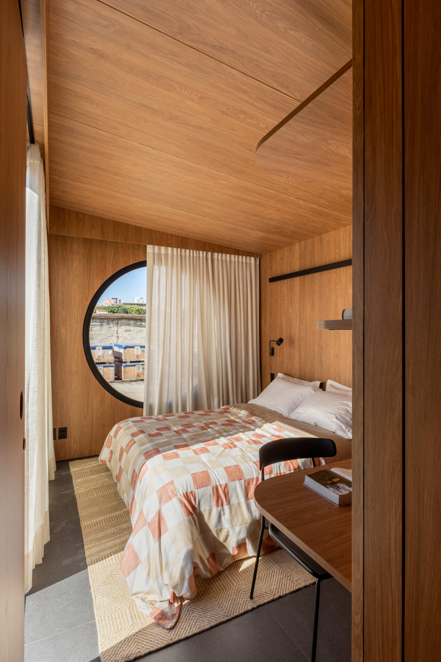 Explore the space-saving layout of Casa M38, a small prefab home with an open kitchen and living room, an integrated dining table, a private bedroom with a workspace, and a bathroom.