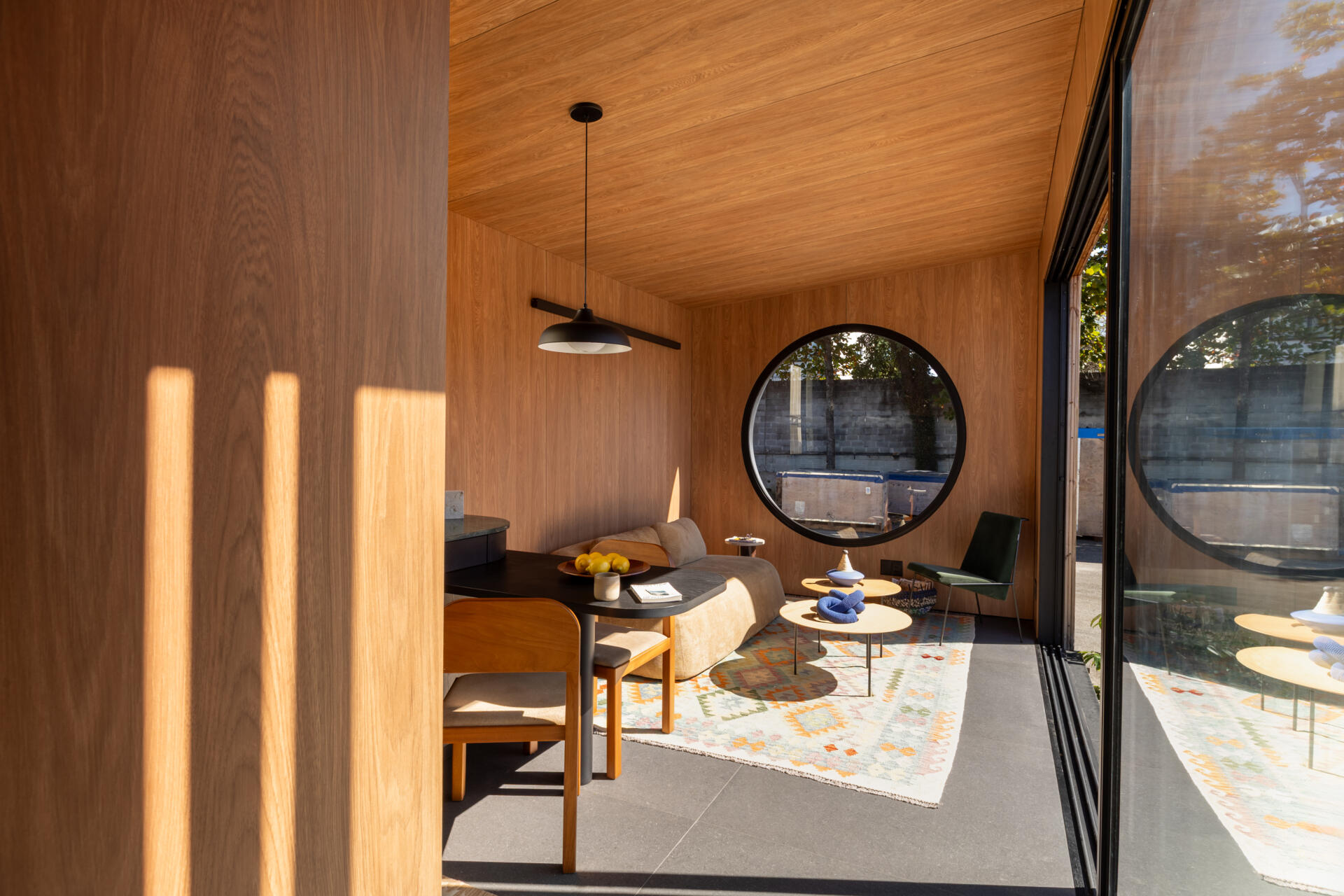 Explore the space-saving layout of Casa M38, a small prefab home with an open kitchen and living room, an integrated dining table, a private bedroom with a workspace, and a bathroom.