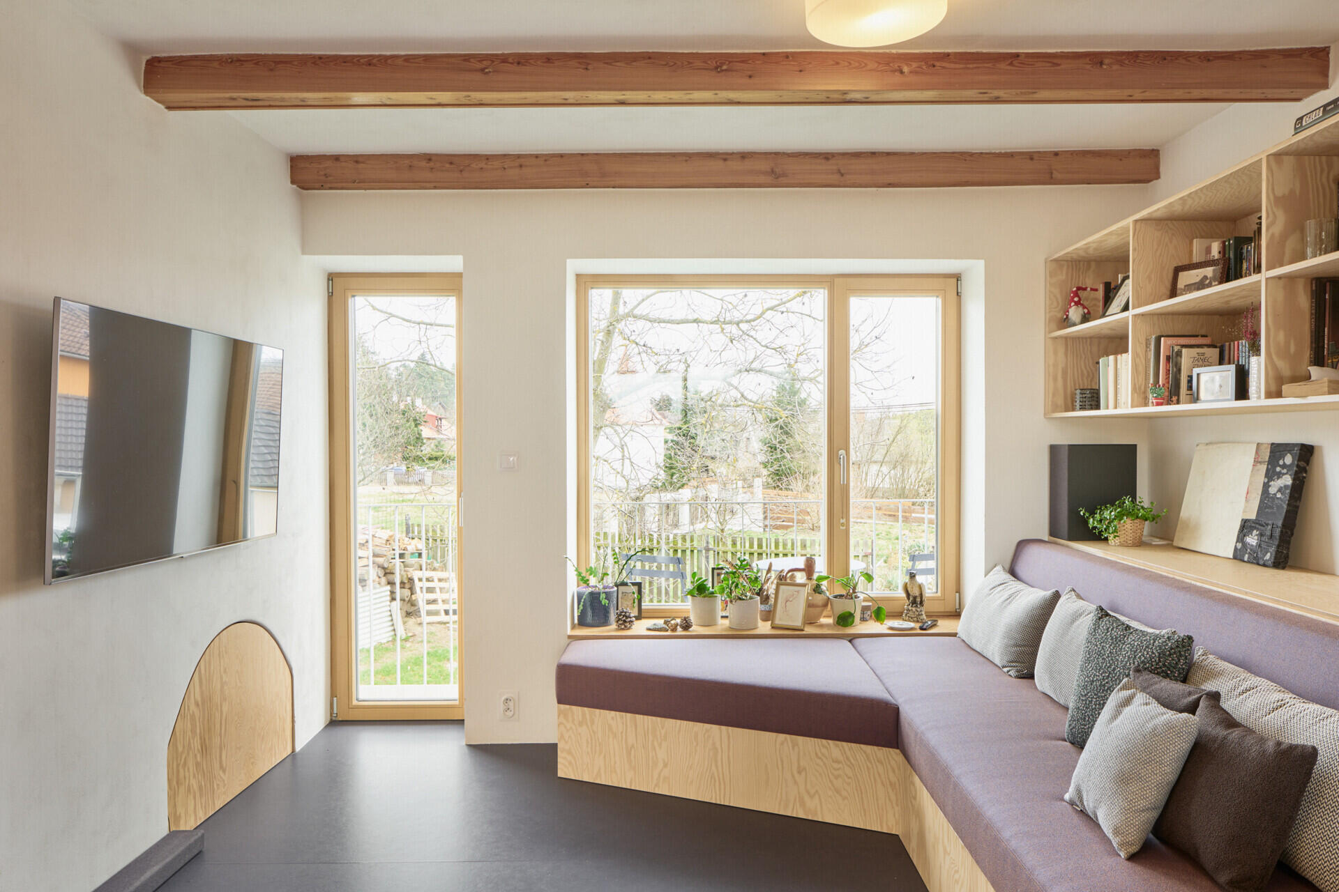 Custom pine plywood furniture transforms part of this renovated Czech home by Facha architekti into a relaxed secondary living space, with built-in seating, bookshelves and storage making efficient use of the compact interior.